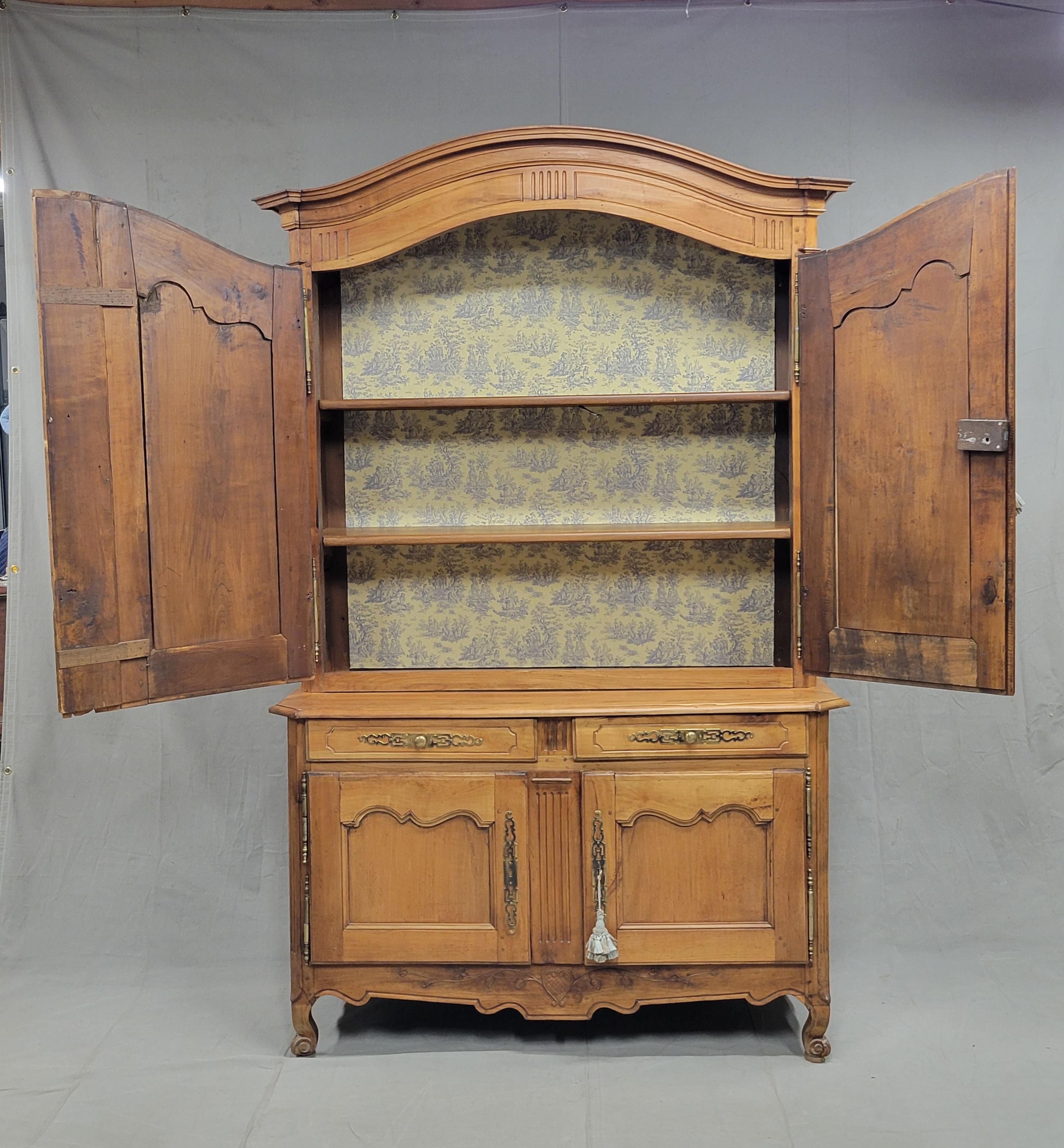 A large, antique French Provincial Louis XV 18th Century Deux-Corps (two piece) cherry buffet cabinet with a blue and pale yellow toile interior. The cherry wood glows with a lightly waxed finish. Note the charming carved heart detail in the center