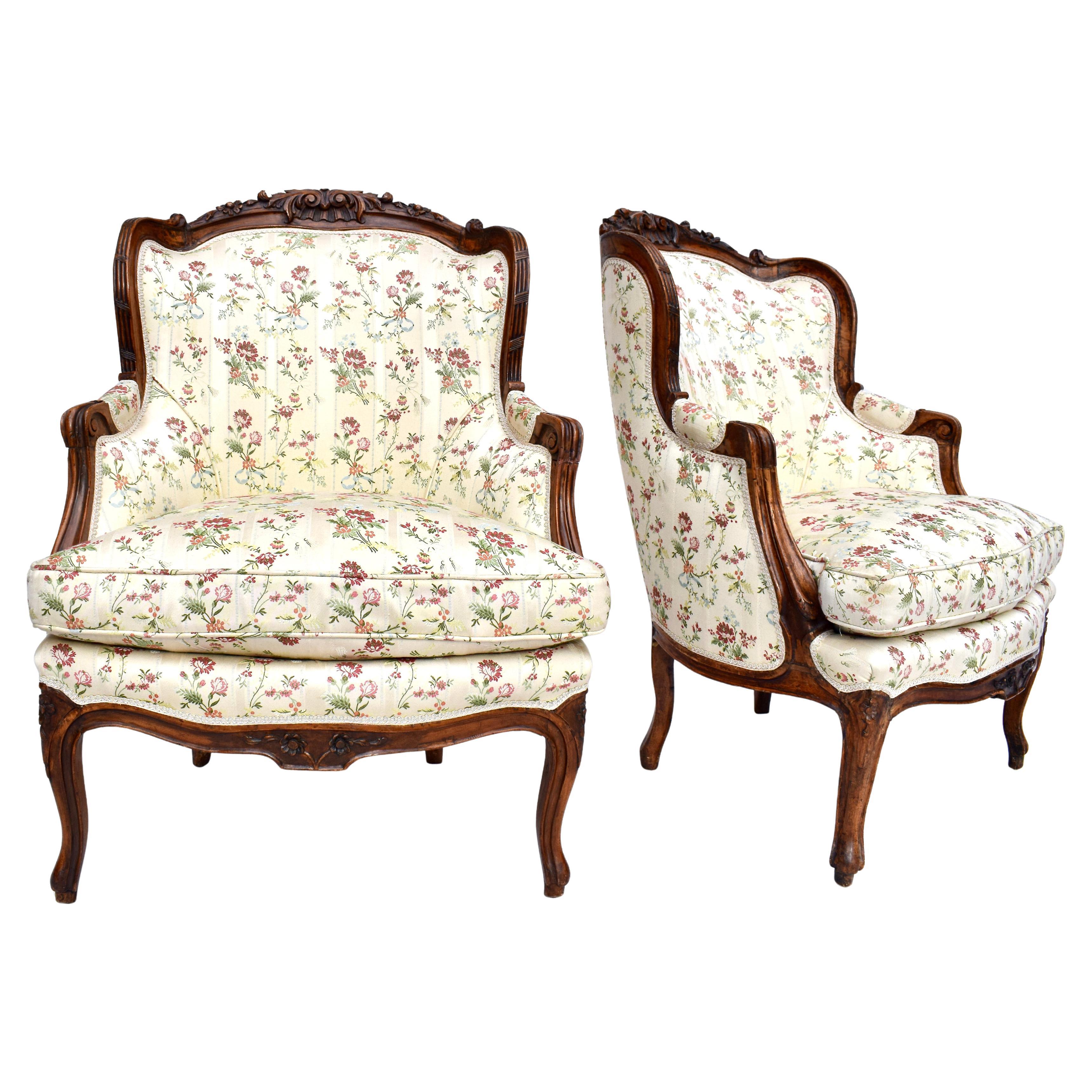 A pair of Intricately hand carved mid 19th C. French Bergere chairs upholstered in Scalamandre floral silk with plump goose down loose cushions. Seat Height: 21