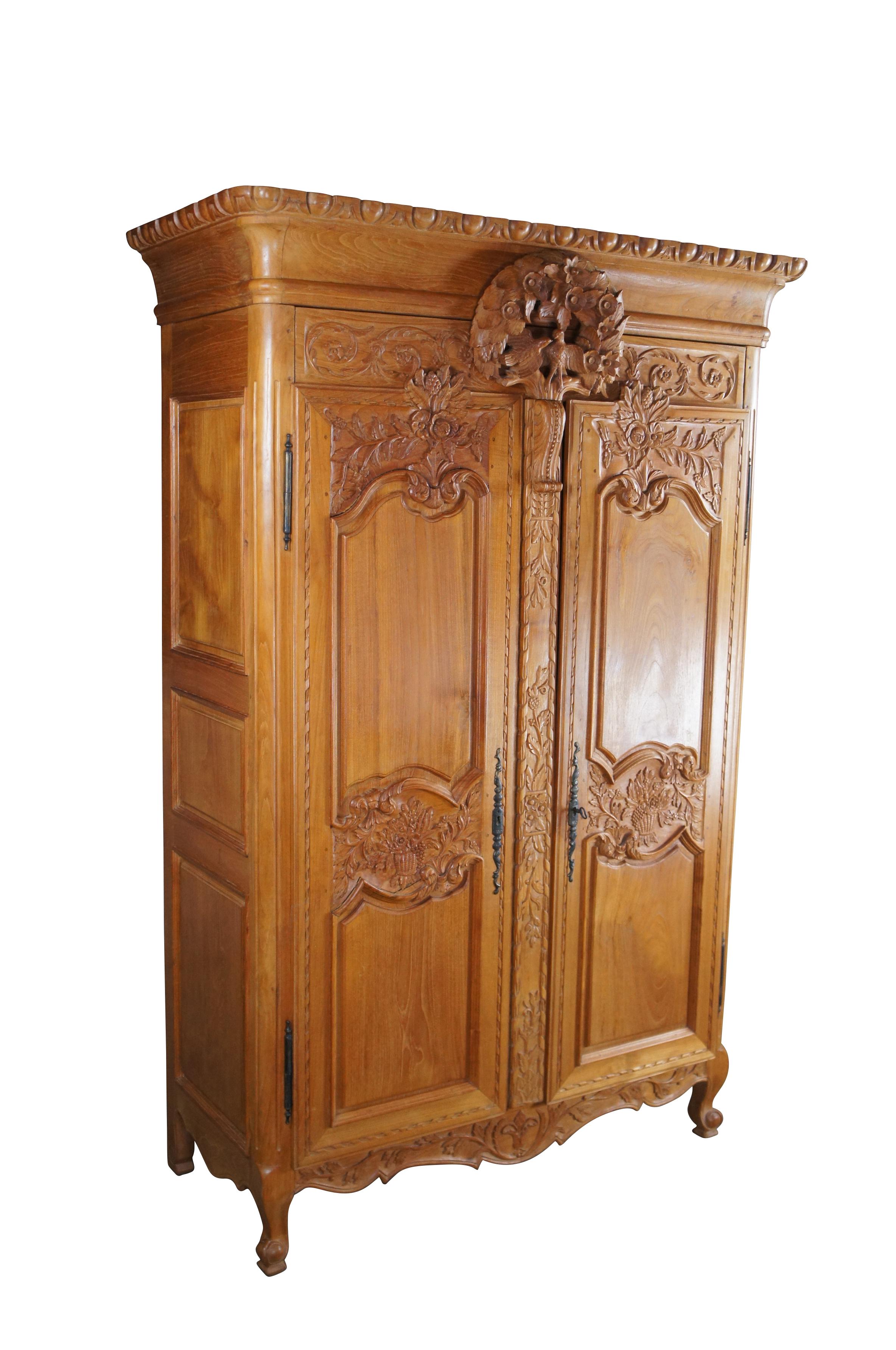 Antique French Louis XV knockdown wedding armoire / wardrobe / linen press.  Made of mahogany featuring baroque styling with carved egg and dart crown over a floral and bird theme wreath and paneled doors with foliage and fruit basket