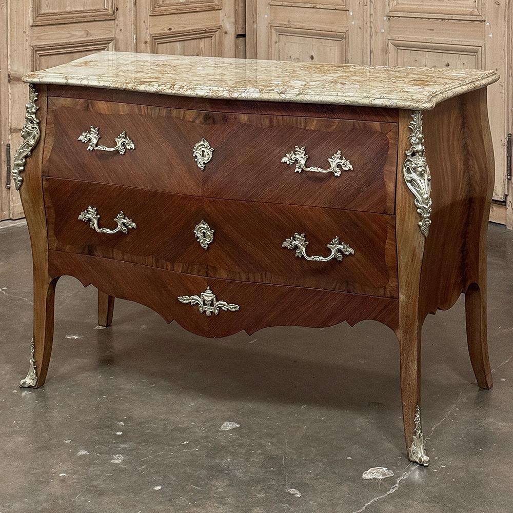 L'Antique French Louis XV Bombe Marble Top Commode presenta la classica forma francese che risale al periodo barocco del XVII secolo.  Su tutti e quattro gli angoli compaiono dei sinuosi montanti angolari, mentre quelli anteriori sono impreziositi