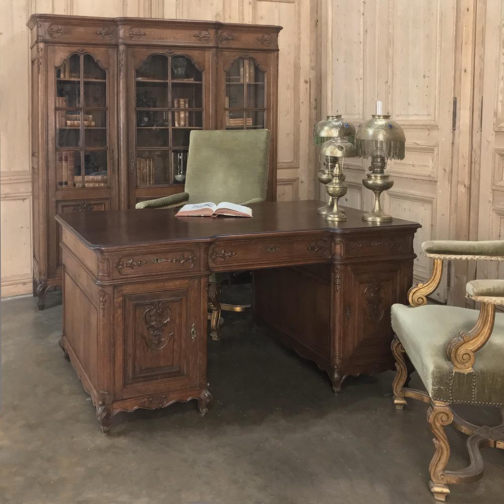 Antique French Louis XV Bookcase, rendered in solid oak, features a step-front design that combines with the bas relief carvings to create visual appeal from any angle! Arched glazed panes above provide a splendid display for books, keepsakes, or