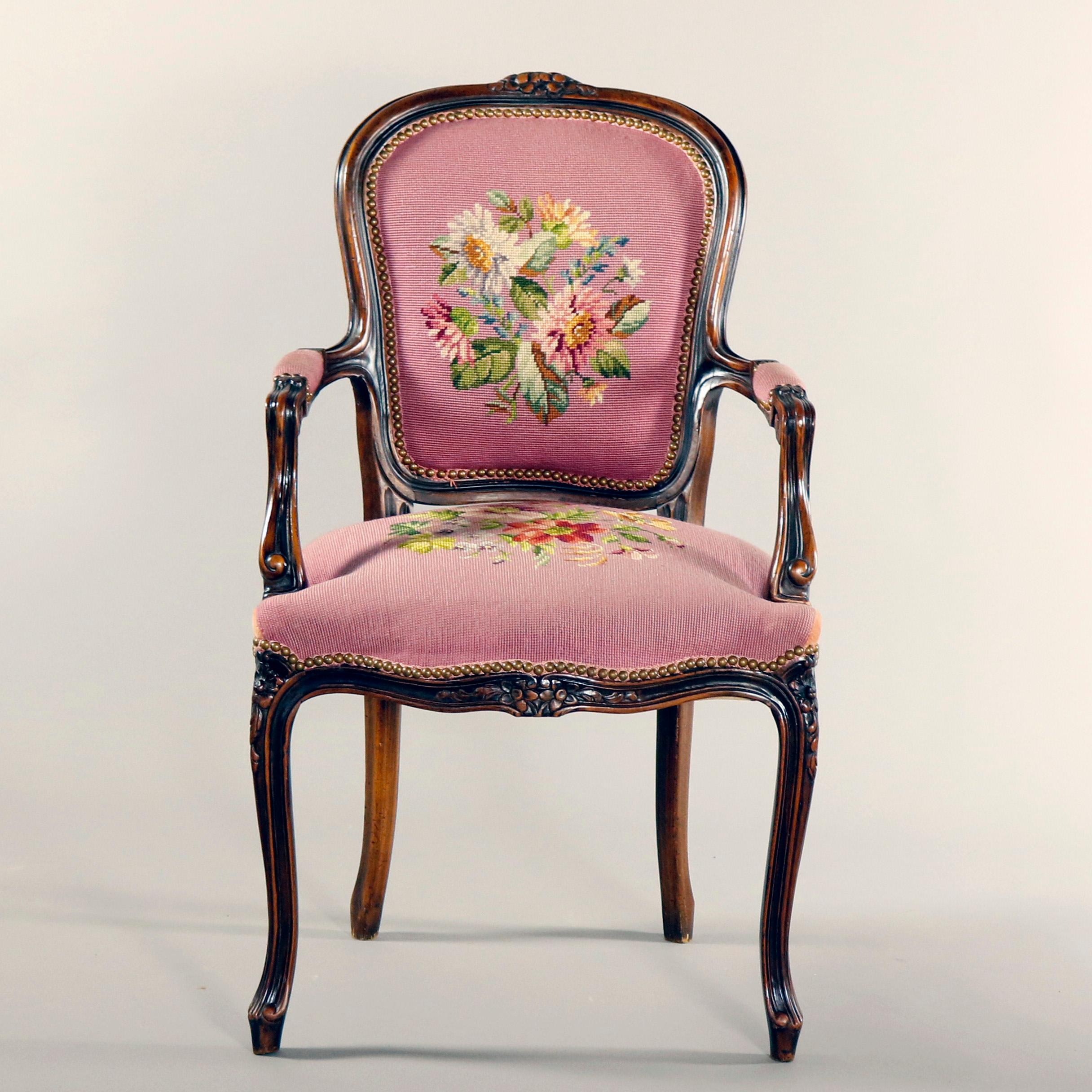 An antique French Louis XV style armchair features walnut frame with carved floral crest and apron, scroll arms and raised on cabriole legs, upholstered in floral needlepoint, circa 1900

Measures - 38