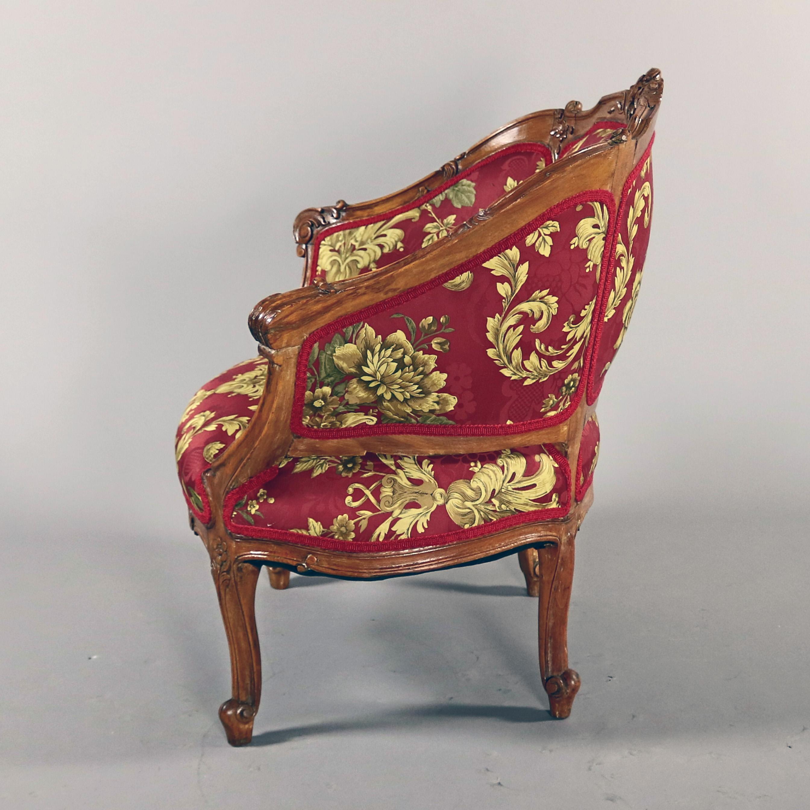 An antique French Louis XV Louis XV bergère armchair offers carved walnut frame with carved stylized shell crest, scroll ed arms and raised on cabriole legs with carved floral and scroll decoration, more recently upholstered, 18th