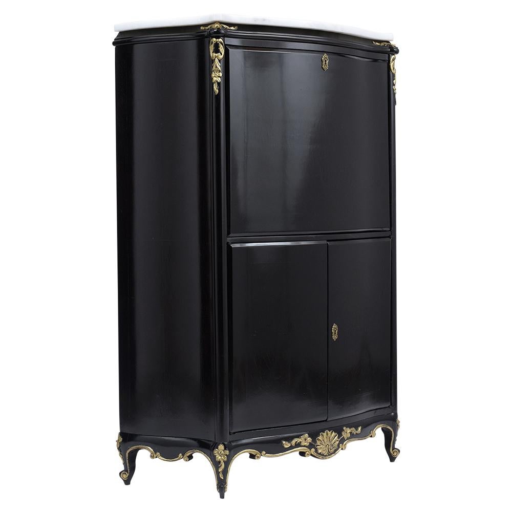 This French Antique Louis XV Secretaire has been restored, is made out of mahogany wood, and features an ebonized lacquered finish with gilt details. The Secretaire comes with a new white marble top, curved sides, a droptop desk, and the interior