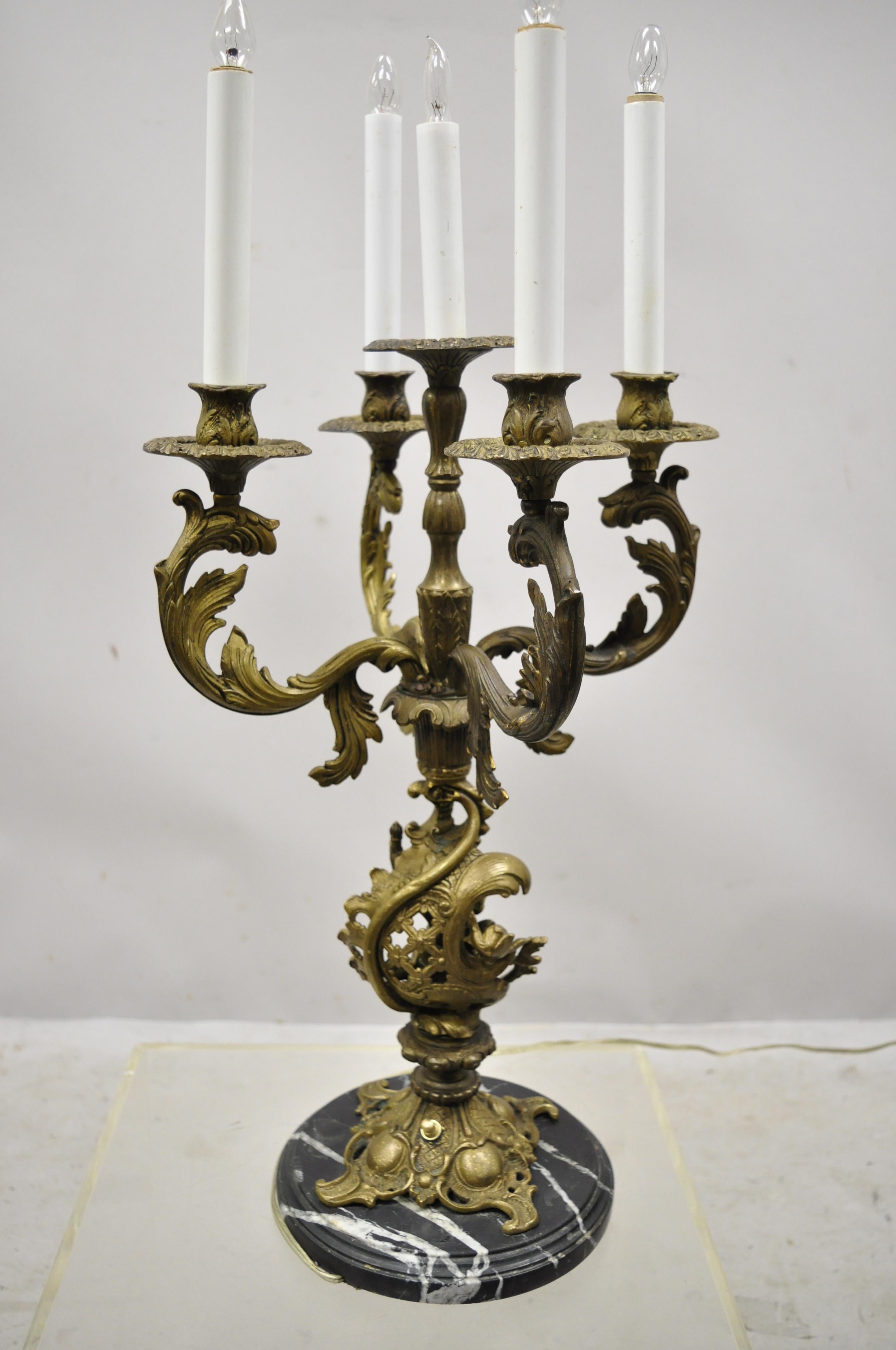 Antique French Louis XV style figural cherub brass and marble candelabrum table lamp. Item features round black marble base, 5 candelabras, figural cherub to center, ornate acanthus arms, great style and form. Has holes for prisms on the bobéches if