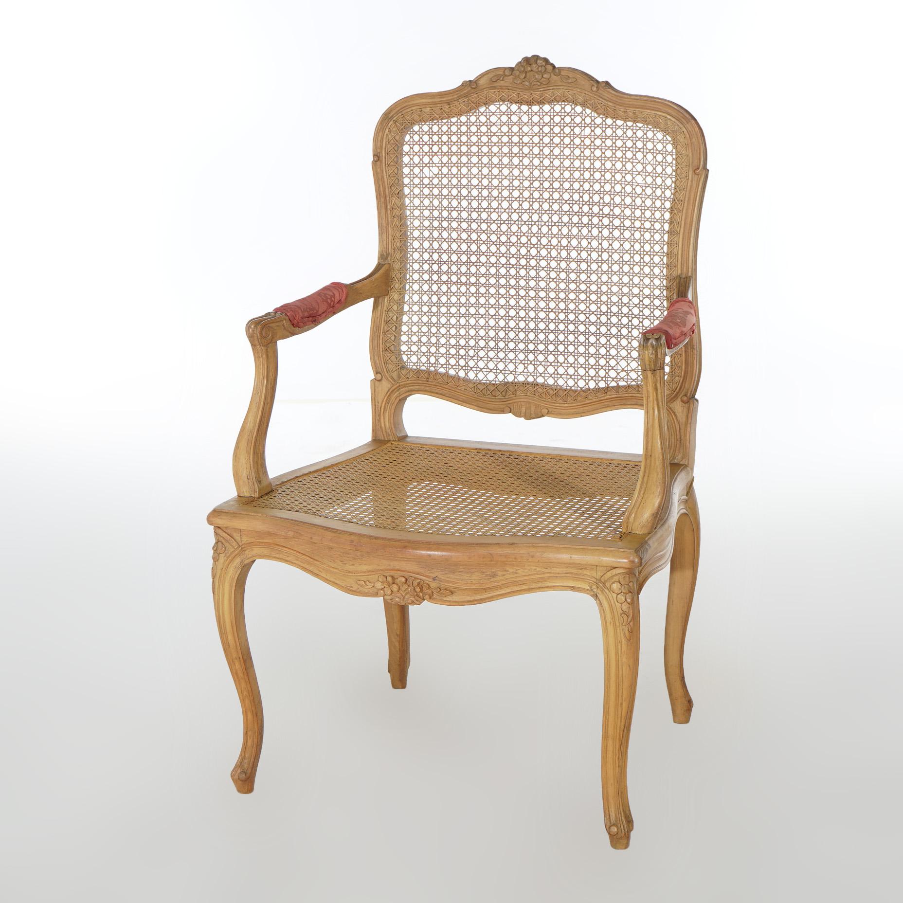 An antique French Louis XV style arm chair offers carved fruitwood frame having floral crest over caned seat and back, covered arms and raised on cabriole legs, c1900

Measures - 39.5