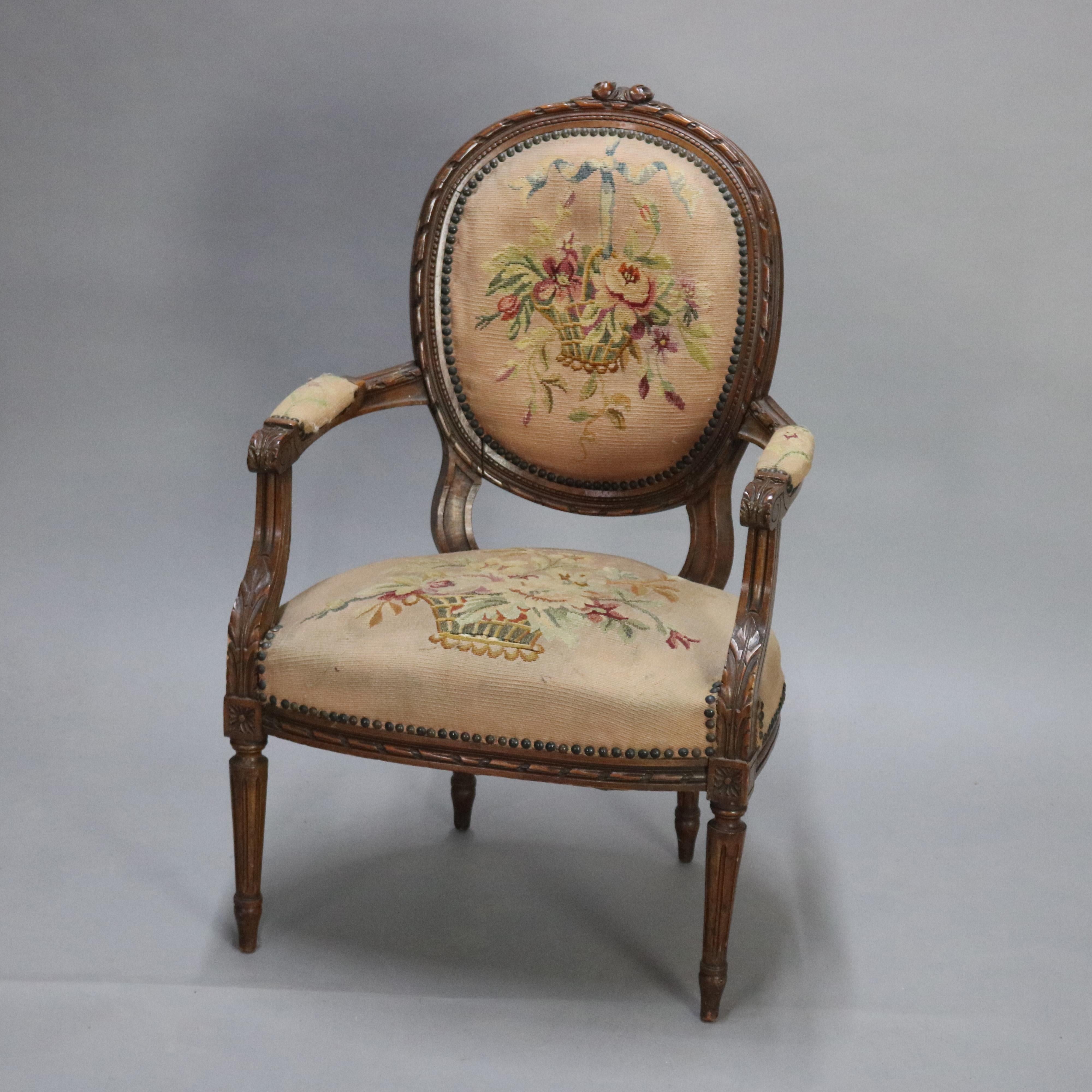 An antique French Louis XV armchair offers carved fruitwood frame with carved floral crest and ribbon form frame, rosettes, acanthus arms, floral panier de fleurs needlepoint back and seat, raised on tapered reeded legs, 19th century

Measures: