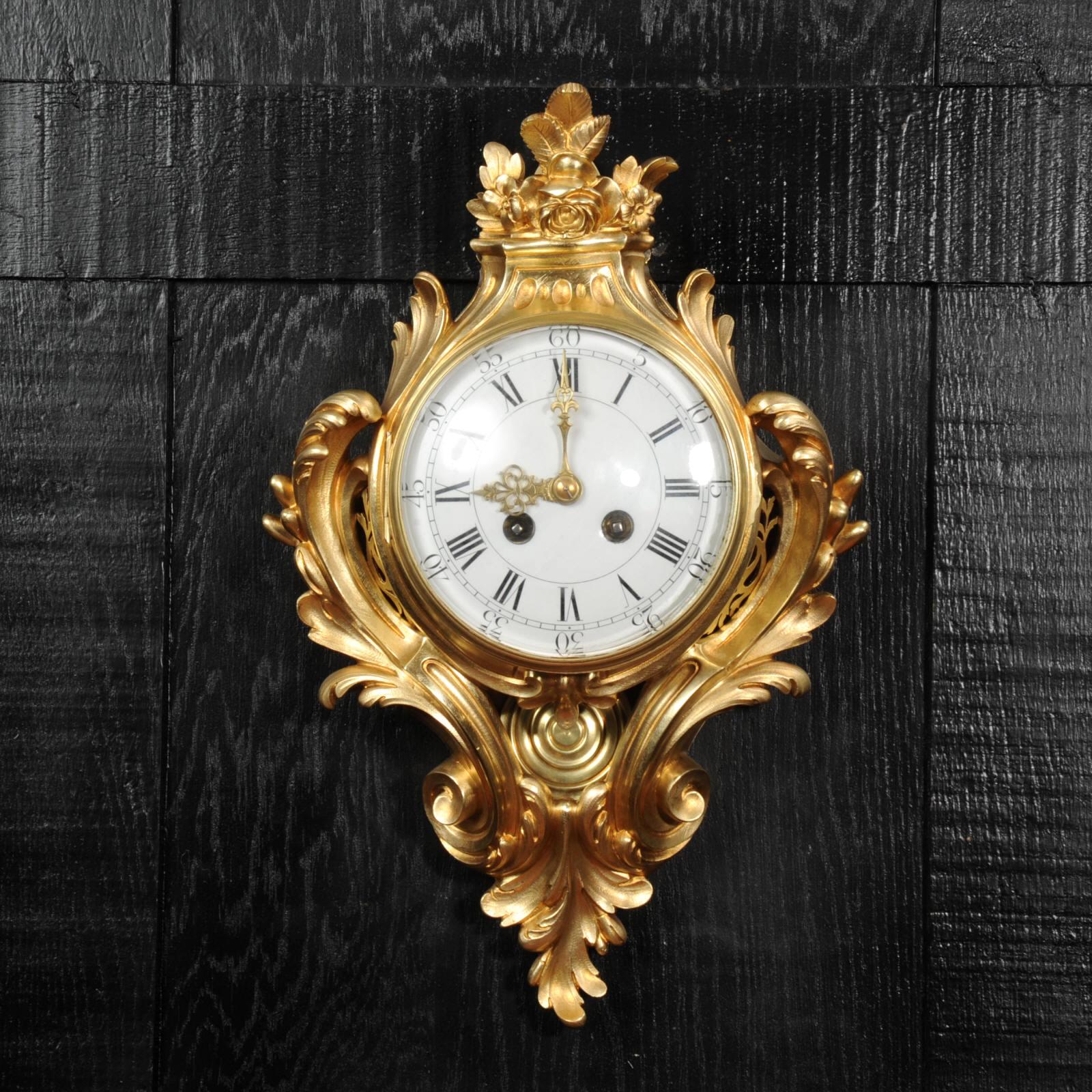 A beautiful, original antique French gilt bronze cartel wall clock. Stunning Louis XV Rocaille design with bold scrolling acanthus leaves and a foliate finial. To the sides are fretted apertures and the pendulum is visible gently swinging below the