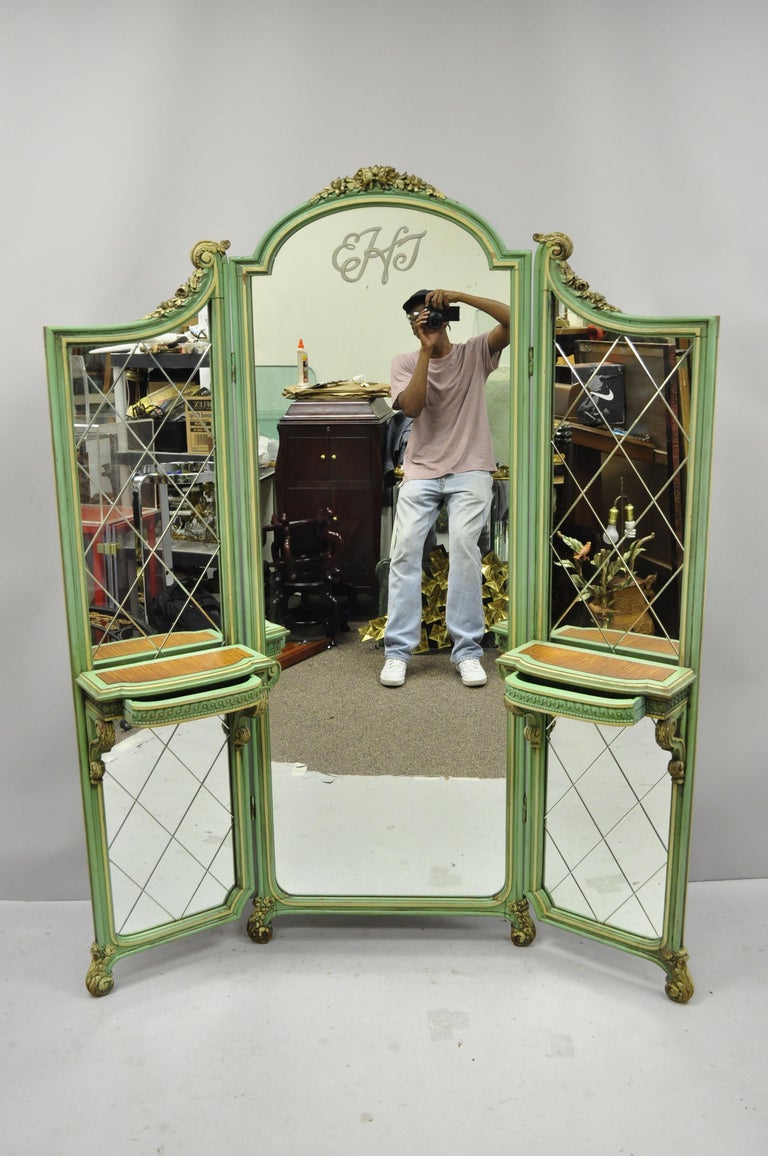 Antique French Louis XV style green and gold three-panel tall folding dressing vanity mirror screen. Item has 2 small dovetailed drawers, etched glass panels, monogram to top center panel, green distress painted finish, three folding sections, very