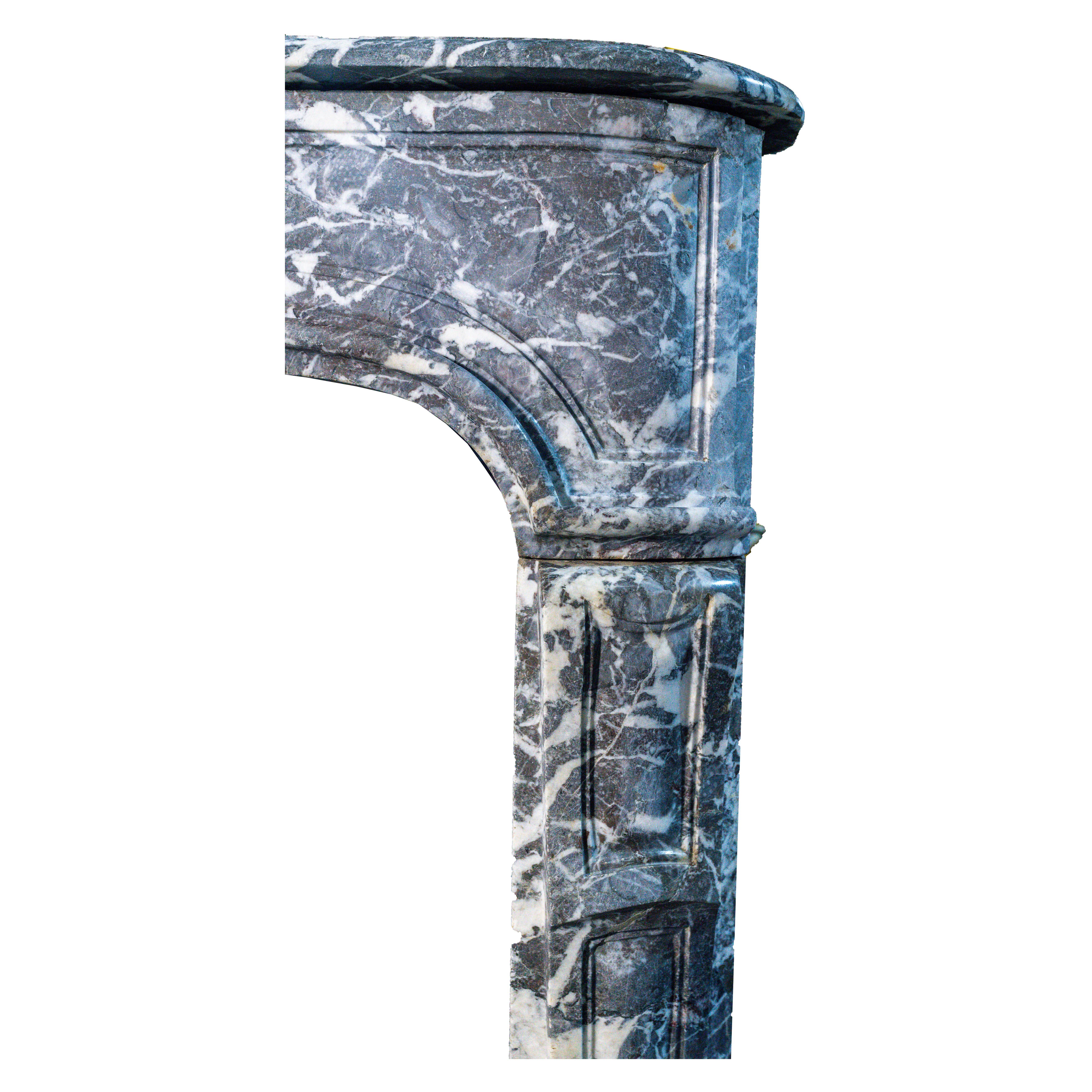 Gracieuse cheminée française de style Louis XV, richement figurée et sculptée dans un marbre gris veiné, datant d'environ 1750. Cette pièce élégante incarne l'esprit rococo avec ses lignes doucement incurvées, sa frise serpentine et son subtil