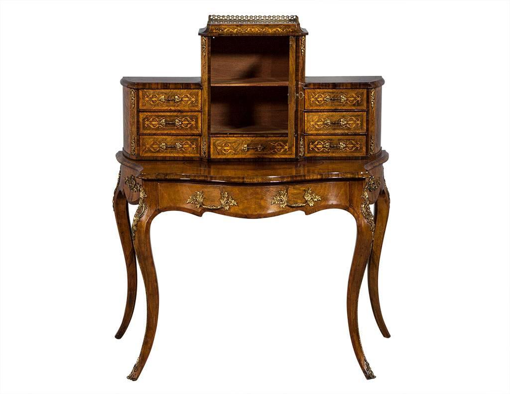 This Louis XV style vanity desk hails from 1920’s France.  The piece has one wide drawer in front and a taller middle section with one drawer and a door with a mirror front and shelf inside.  There are three drawers on each side for even more