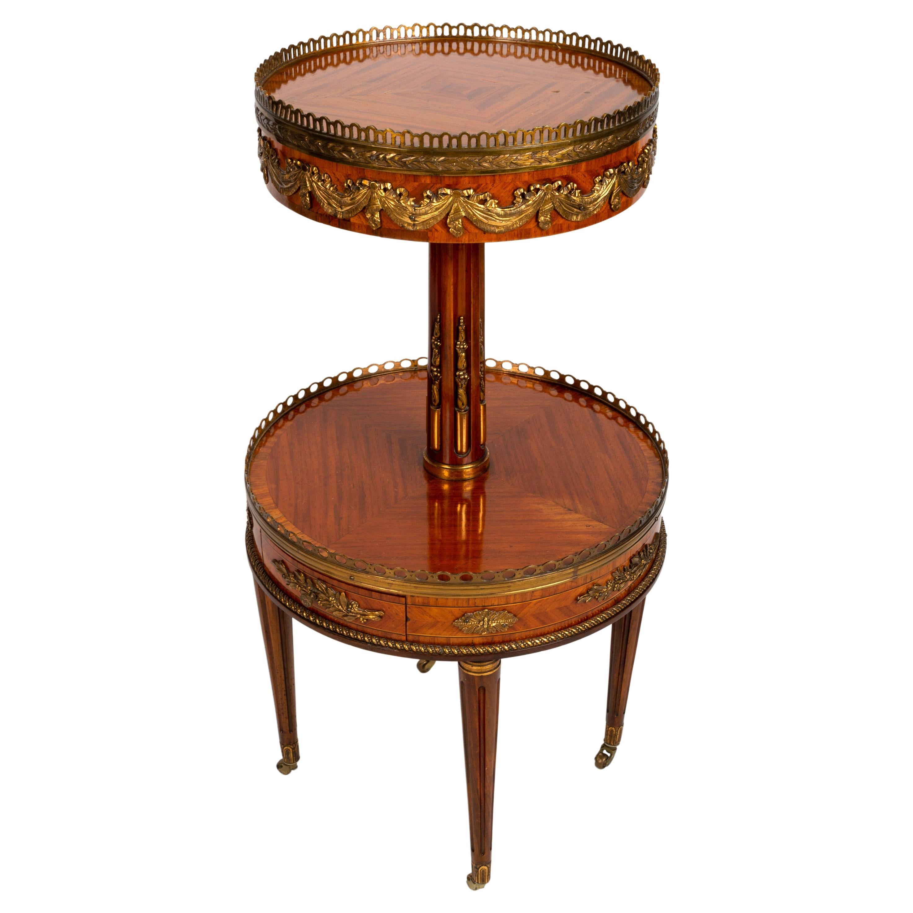 An antique French louis xv revival kingwood and ormolu etagere in the manner of francois linke, late 19th century

The circular quarter veneered and cross banded top with a pierced brass gallery and gilt metal swags, on a fluted stem, over a