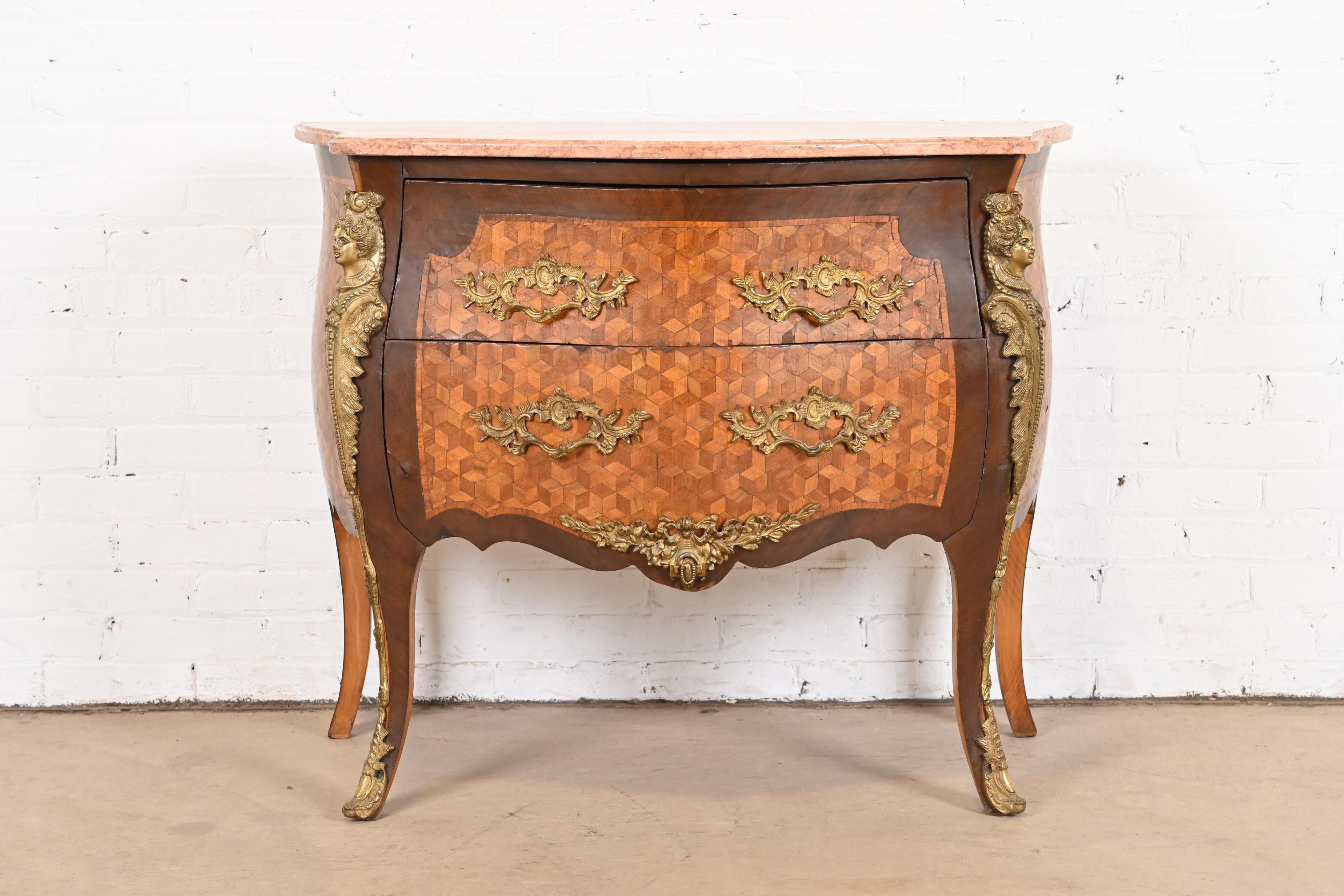 A gorgeous antique French bombay commode or chest of drawers

France, Early 20th century

Mahogany, with inlaid satinwood parquetry, mounted bronze ormolu, and beveled pink marble top.

Measures: 40