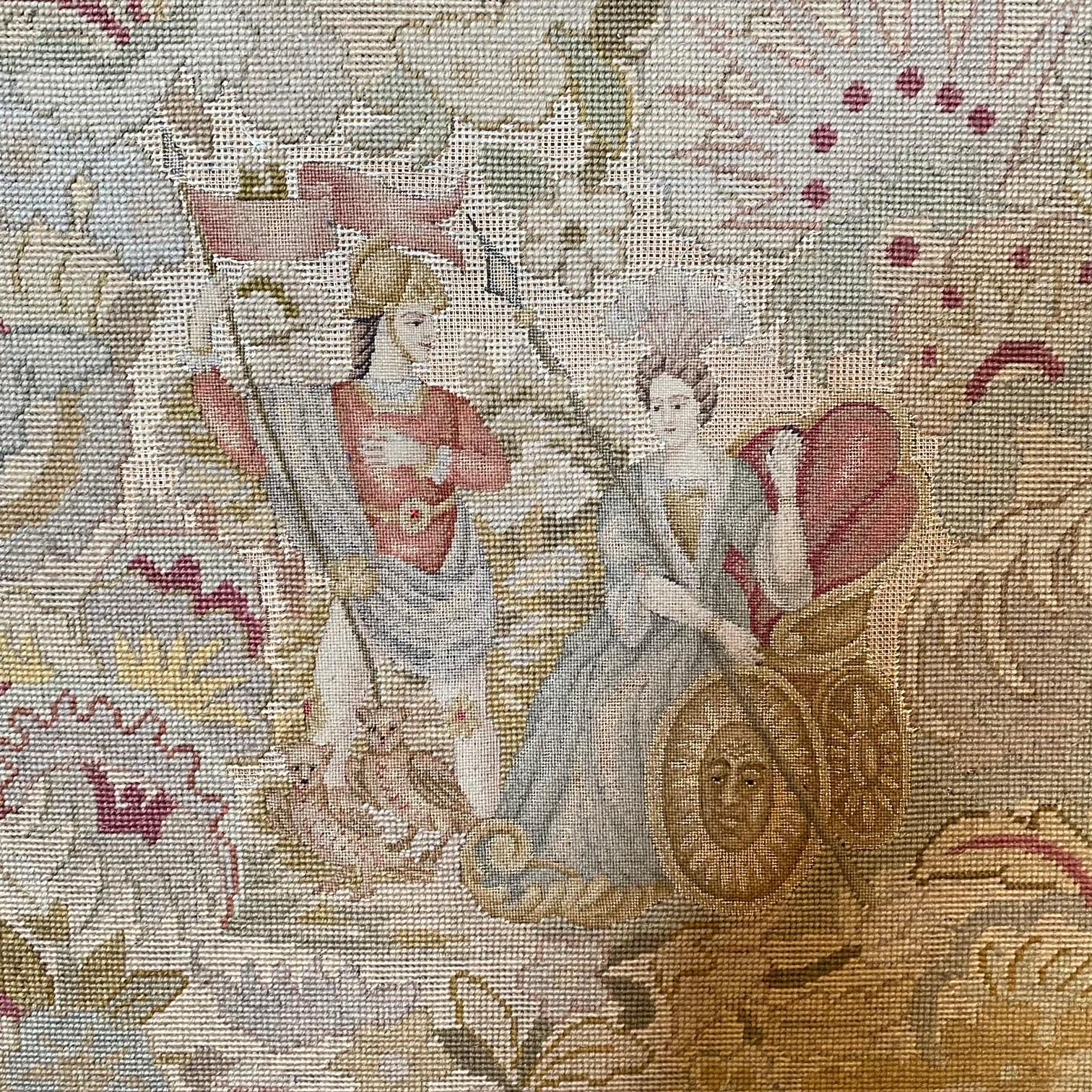 Exquisite carved walnut French needlepoint fireplace screen showcasing a figural pair of gods, with a captivating floral design delicately embroidered on the back. Crafted with meticulous attention to detail, the intricate petit point work showcases