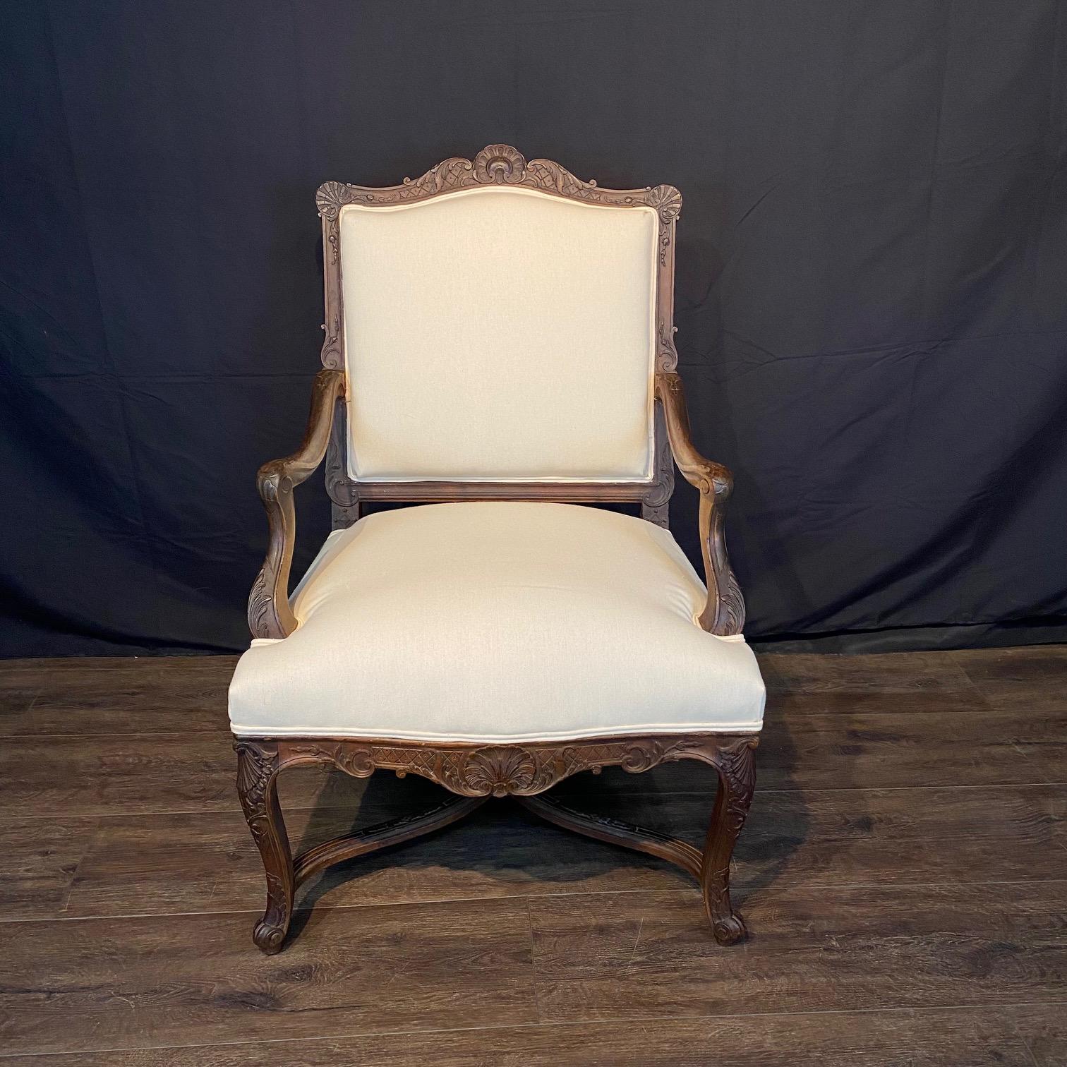 Eleganti poltrone francesi d'epoca Luigi XV in noce, con seduta e schienale rivestiti di recente in tessuto neutro di alta gamma bianco crema. Ricca decorazione Regency intagliata sul retro e sul grembiule con conchiglie e foglie d'acanto, e poggia