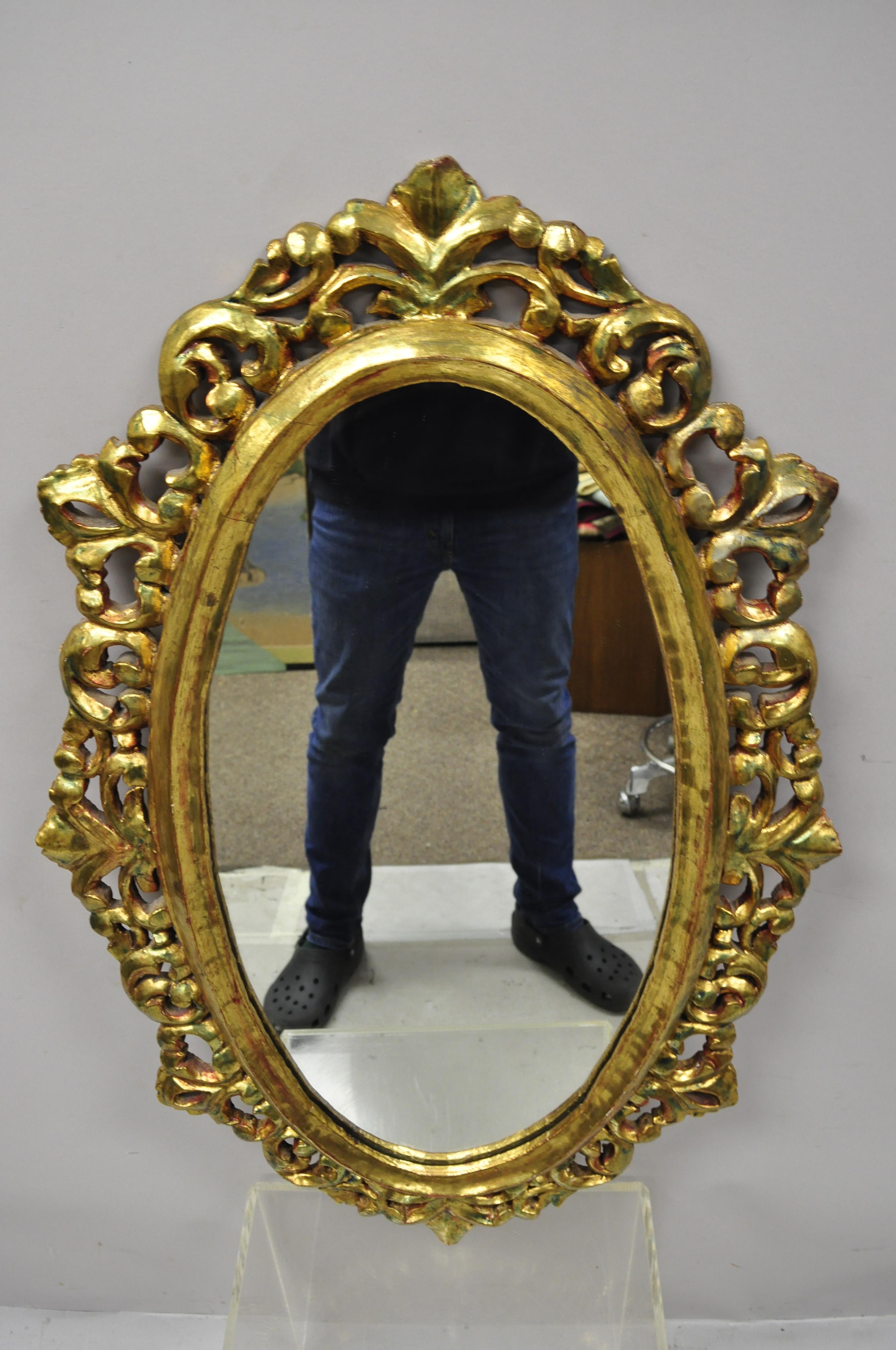Antique French Louis XV Rococo style gold giltwood pierce carved oval wall mirror. Item features gold gilt finish, solid wood frame, nicely carved details, great style and form. Wood frame appears to be from the early 1900s while the gold finish