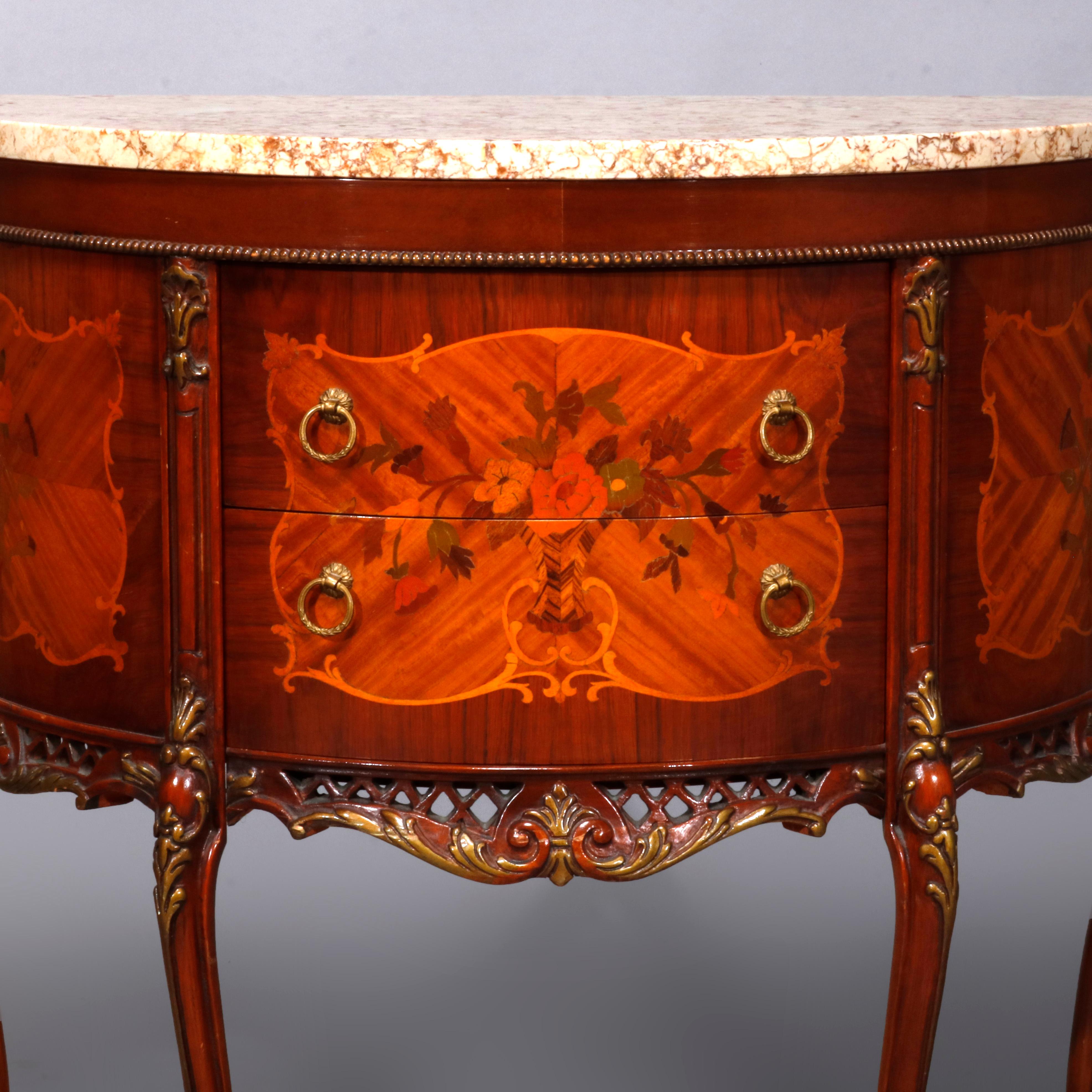 An antique French Louis XV style commode offers demilune form with marble top surmounting mahogany case with central double drawer tower and side panels with satinwood inlaid marquetry in floral, carved and pierced foliate apron and raised on