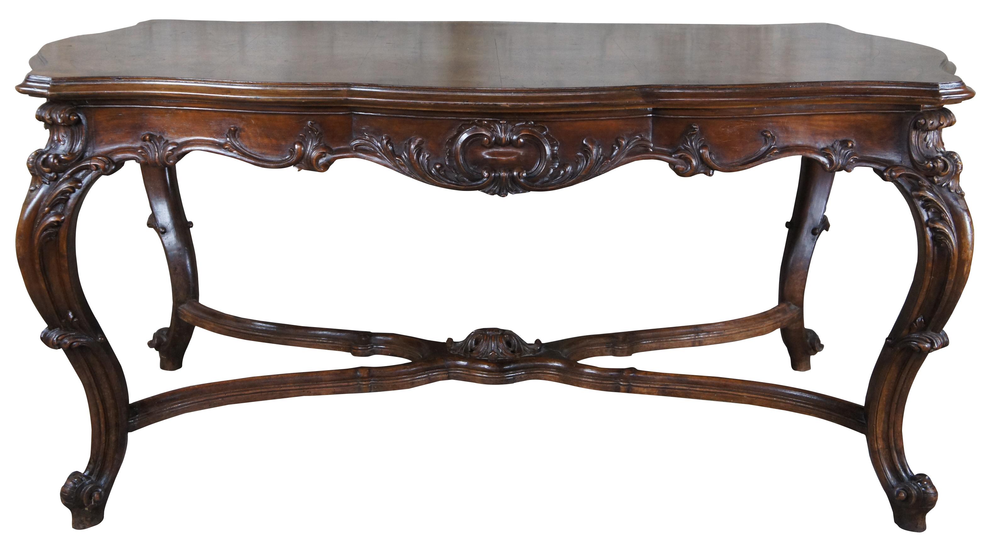 Antique French Louis XV dining table or library desk. Made of walnut featuring burl matchbook top with serpentine form and high relief carved acanthus accents, and cabriole legs connected by stretcher with central medallion. Measure: 68