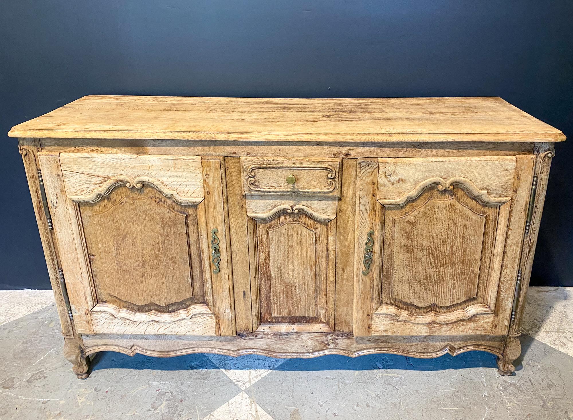 This antique French oak buffet features two side doors and a center drawer for ample storage. The narrow depth of this piece is ideal for dining spaces or as an entry or hallway piece, or could be used as a media storage piece. The doors both have