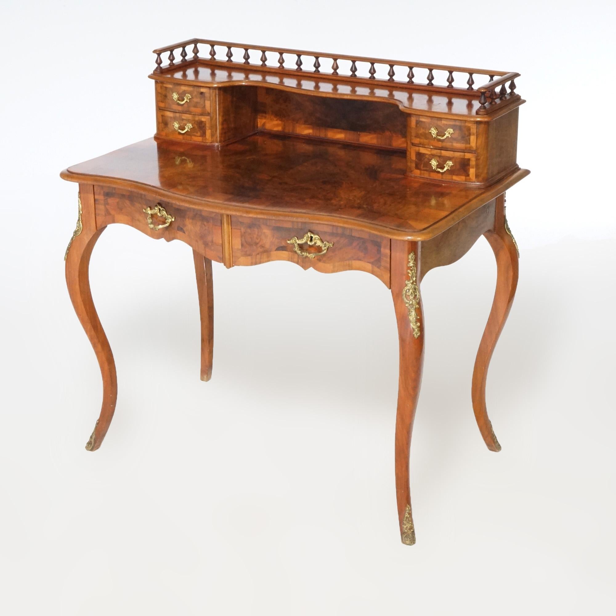 An antique French Louis XV ladies writing desk offers burn and mahogany construction in serpentine form with upper gallery having storage drawers and spindle rail over desk with shaped top, drawers, ormolu mounts and raised on cabriole legs;