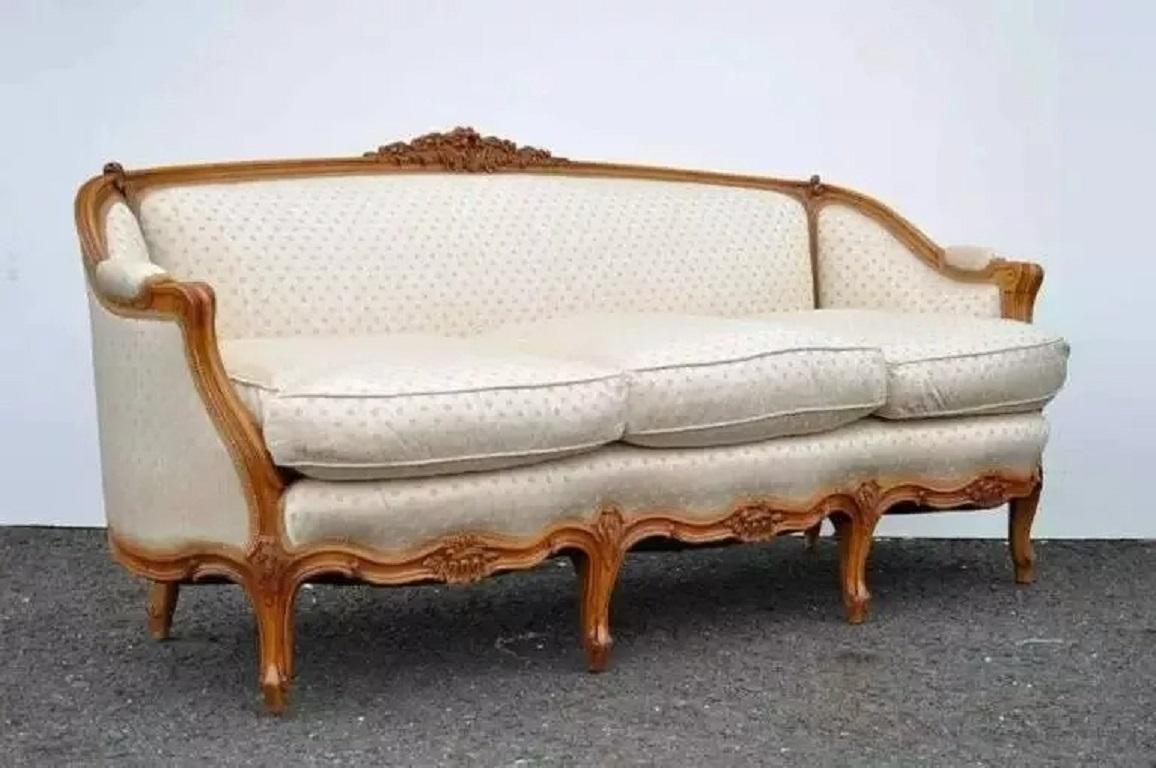 Canapé ancien de style Louis XV en noyer sculpté et doré. Cet article présente de magnifiques accents floraux sculptés, des accoudoirs à volutes et six pieds cabriole, ainsi qu'un joli revêtement beige et or à motif de trèfle avec des coussins