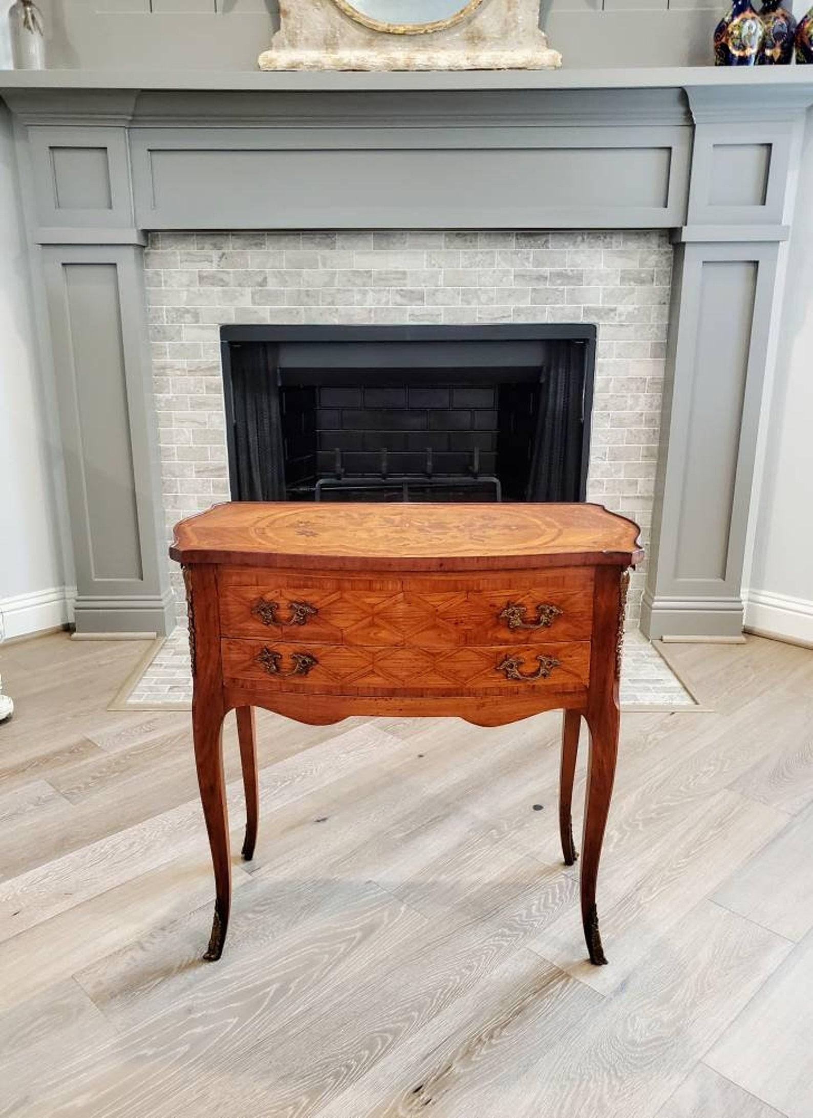 An exquisite French chest of three drawers side table from the early 20th century. The uniquely designed antique finished in elegant Louis XV taste, having a shaped rectangular top featuring beautiful exotic wood inlays of floral marquetry and