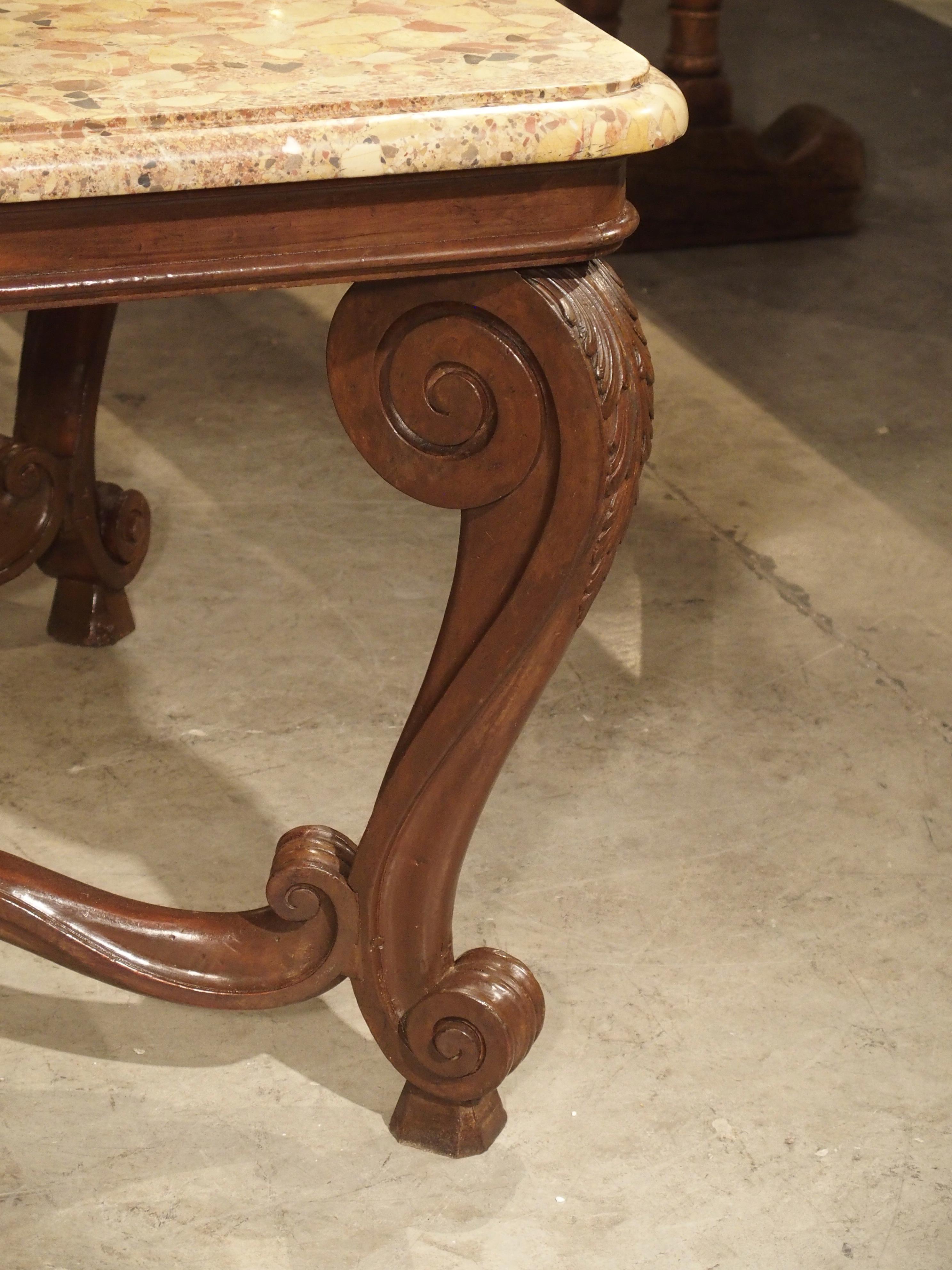 This French Louis XV style dining table from the late 1800s has a sinuously hand carved wooden base with a breche d’alep marble top. Breche d’alep is a type of clastic (composed of old rock fragments) stone that was mined in the South of France and