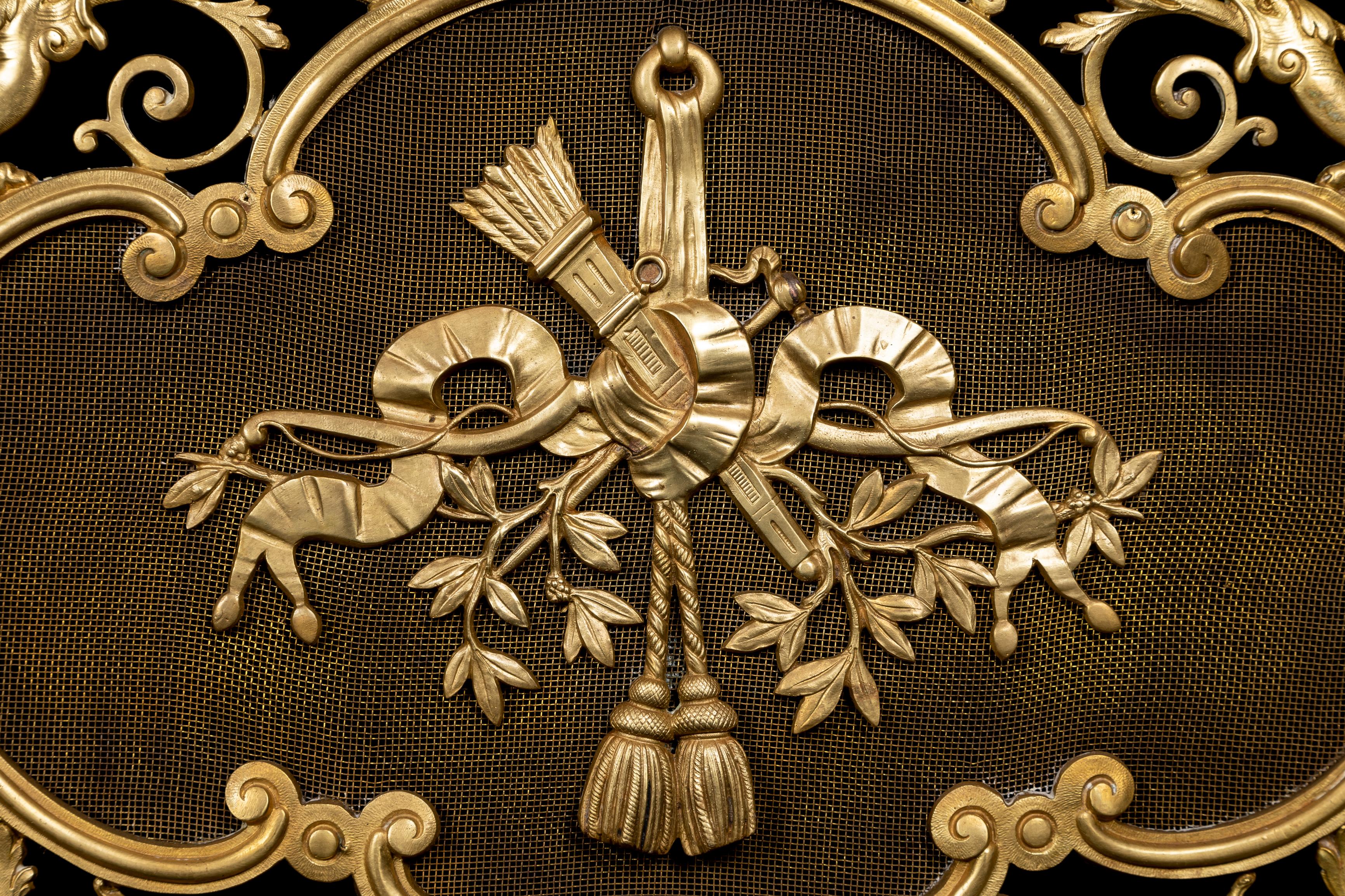 Inusual pantalla de chimenea figurada de bronce dorado de estilo Luis XV francés antiguo, de exquisito detalle. Esta singular pantalla reticulada de bronce dorado está adornada con figuras de maks, dragones y, por último, con una placa central de