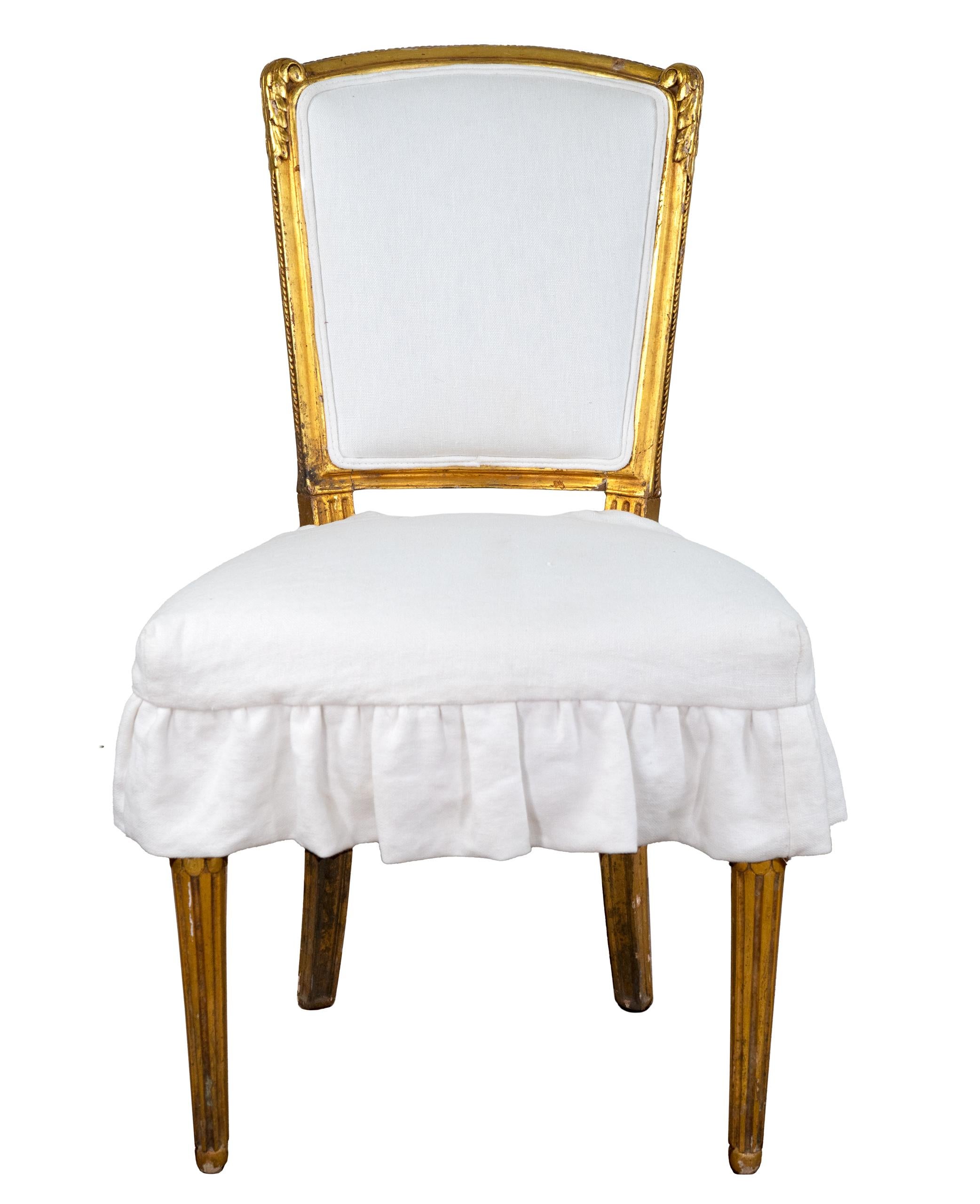 Beautiful pair of antique French gilded accents chairs with new white linen skirted seats. The gilt has areas of aged patina. Wonderful chairs for any area.