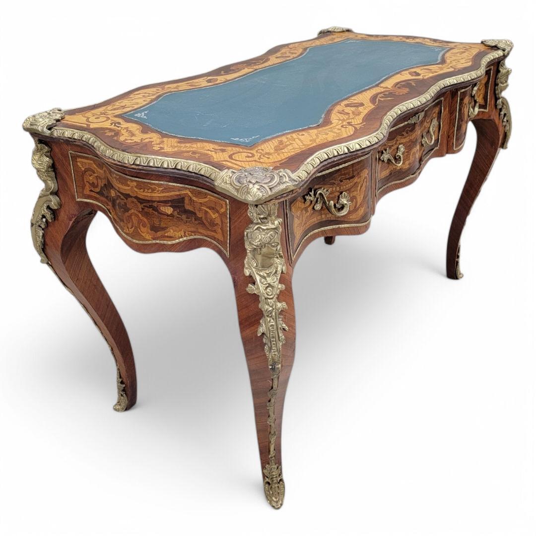 Antique French Louis XV Style Heavily Detailed Inlay Kingswood & Mahogany with Brass Ormolu Mounted Blue Leather Topped 3 Drawer Writing Desk

A stunning piece that combines exquisite craftsmanship with timeless design. This ornate desk features
