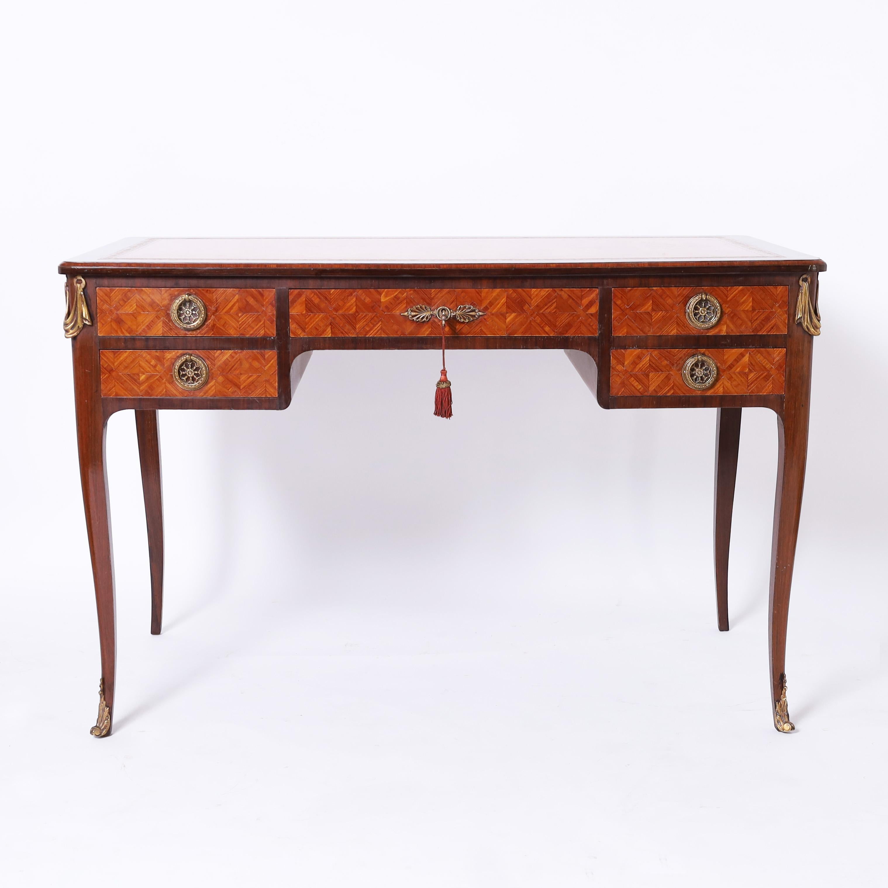 Impressive antique French desk crafted in walnut with a tooled tan leather top on a case with geometric marquetry, five drawers retaining the original hardware and drapery ormolu supported by elegant cabriole legs with acanthus ormolu in the front. 