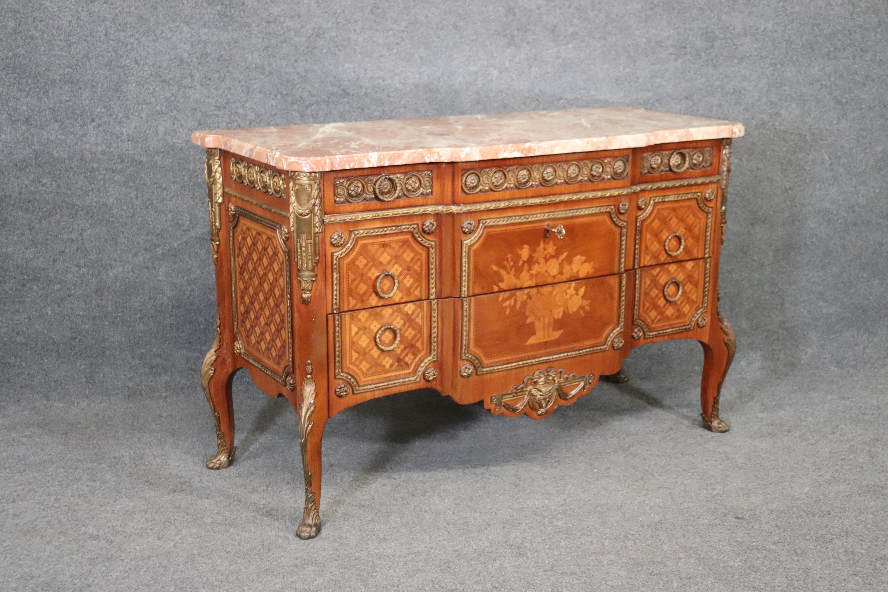 This Antique French Louis XV Style inlaid marble top commode is truly breathtaking! If you look closely at the photos provided you will see the intricate inlaid marquetry design throughout the front and sides of the piece as well as the attention to
