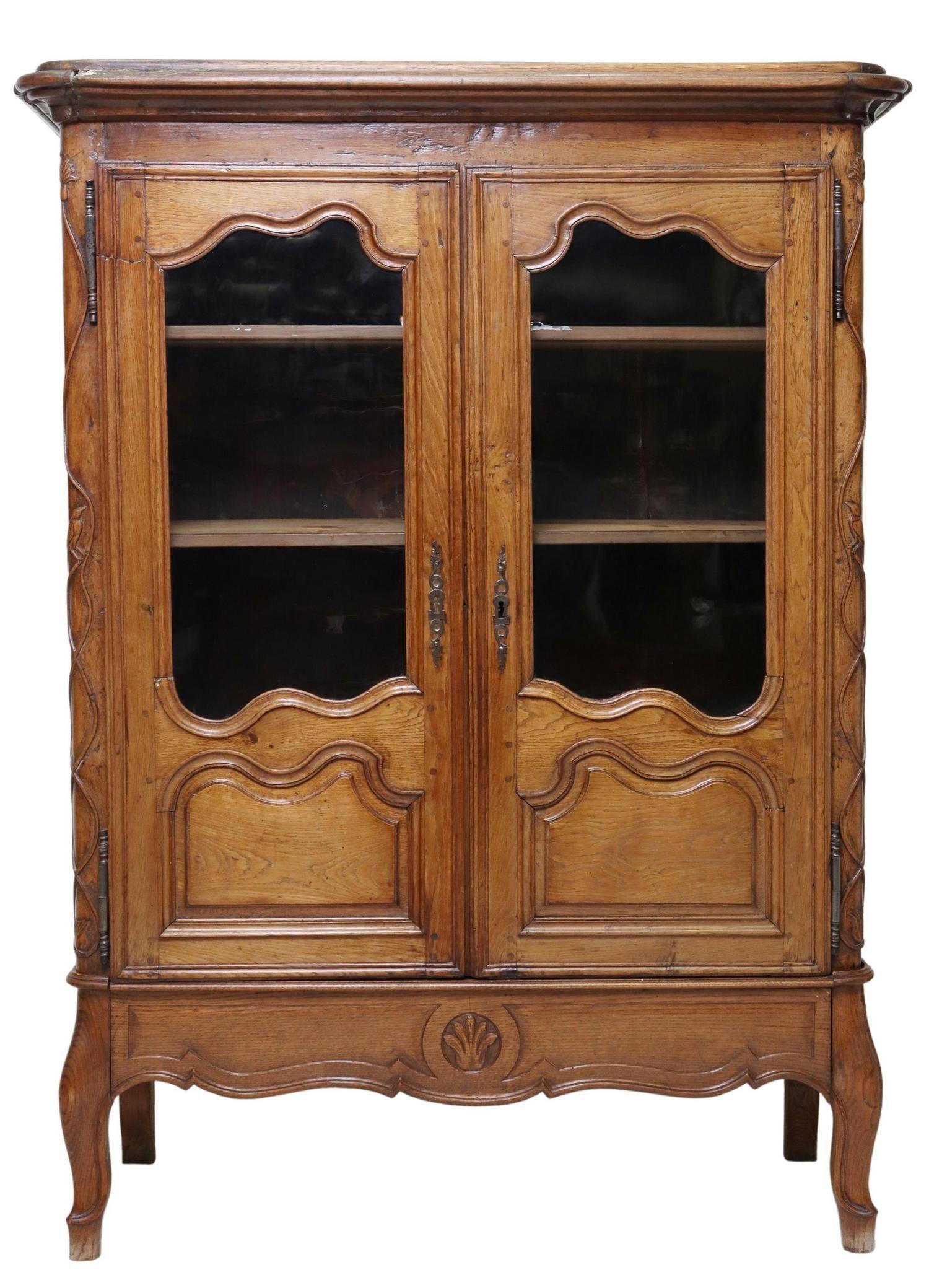 Louis XV style oak cabinet, 18th c/19thc. This cabinet's base was built and added later. The stepped protruding cornice over two partial glazed doors flanked by carved vines and birds, the lower part with a single drawer, rising on cabriolet