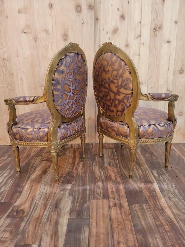 Antique French Louis XV Style ornate carved giltwood fauteuil armchairs newly upholstered - pair.

These elegant and regal French armchairs have a masterfully solid carved wood frames, oval medallion backs, reed and tapered legs, two open arms