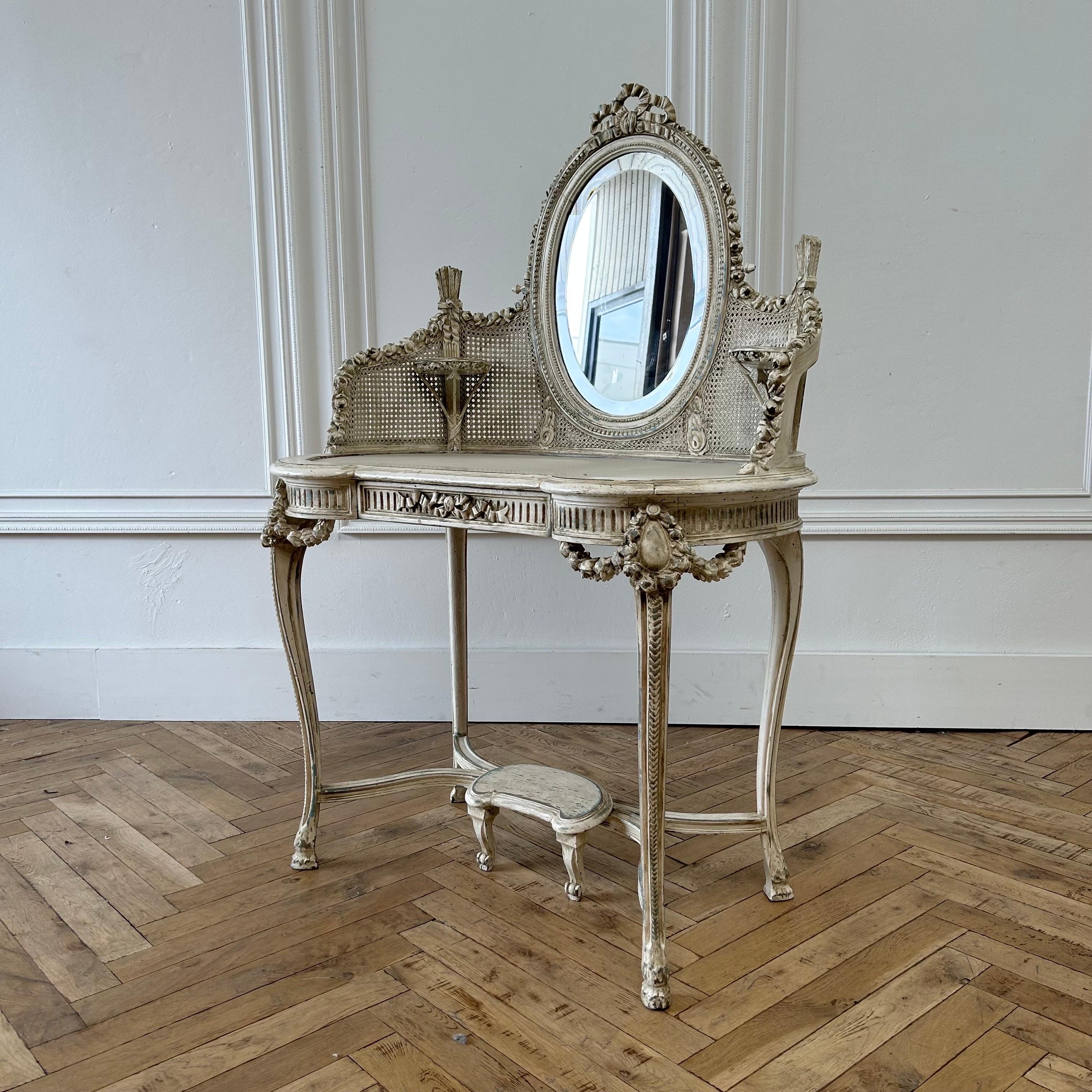 Antique French Style Rose carved vanity 
37”w x 23”d x 54”h 
Vanity top: 29”h
Beautiful original painted vanity, with heavily carved roses trailing down from the ribbon carvings at the top.
Mirror has age spots, cane looks to be overall in good