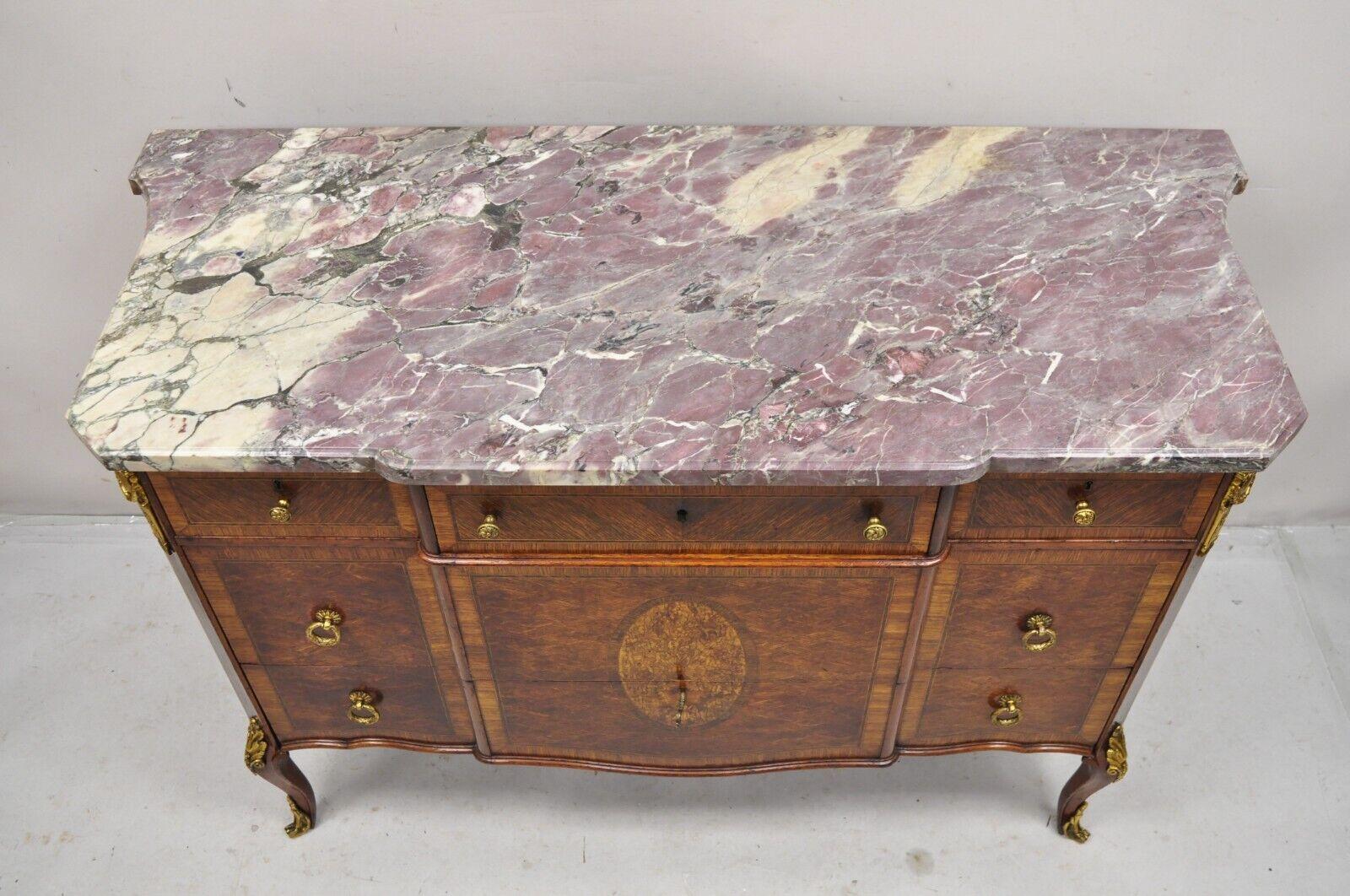 Antique French Louis XV Style Purple Marble Bronze Ormolu Dresser Commode Chest. Item features a shaped rare purple marble top, ornate cast bronze ormolu, floral design satinwood inlay, shaped sides, 5 dovetailed drawers, very nice antique