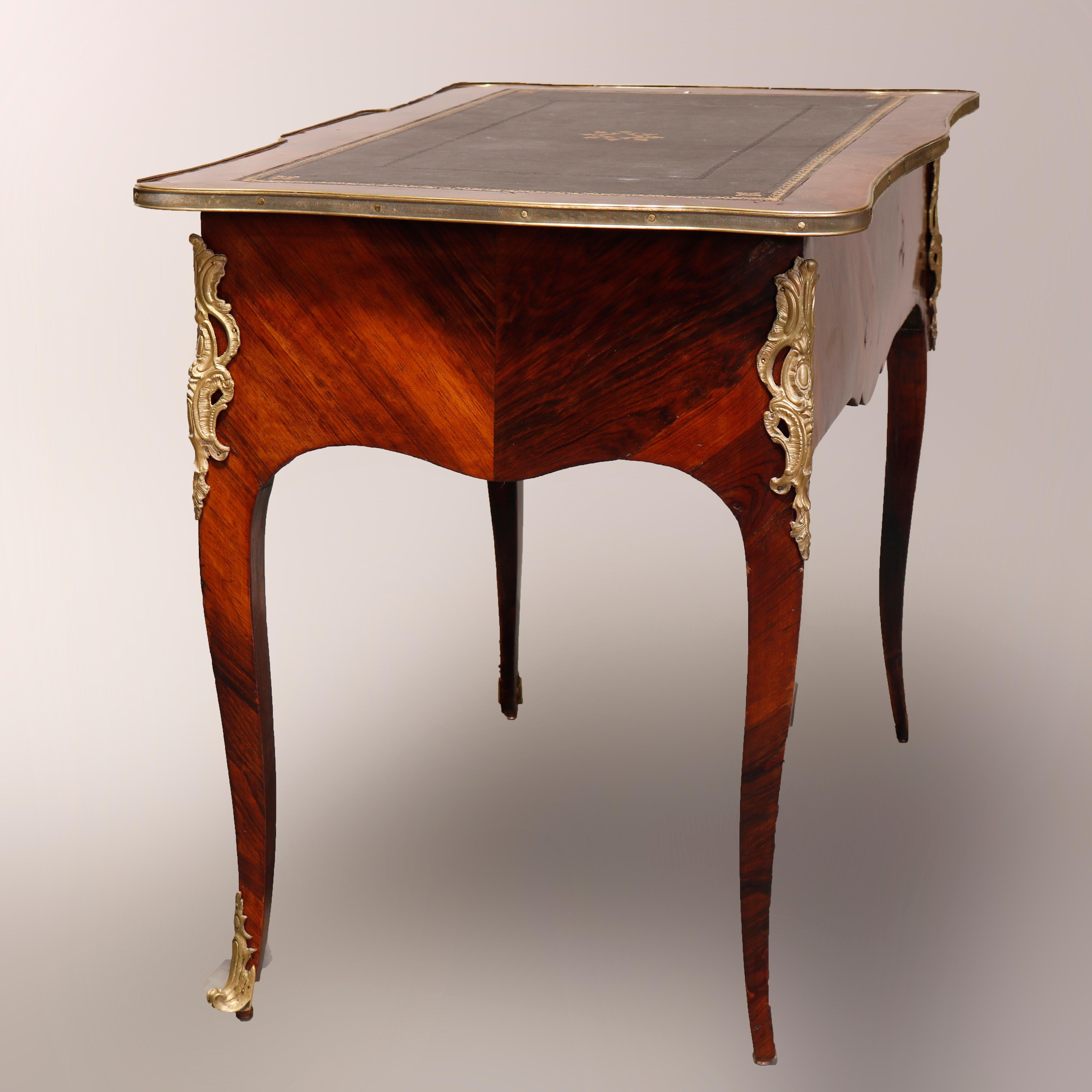 An antique French Louis XV style bureau plat writing desk offers rosewood construction with gilt adorned leather writing surface on shaped top with ormolu mounts throughout, raised on cabriole legs, circa 1890

Measures: 31.25