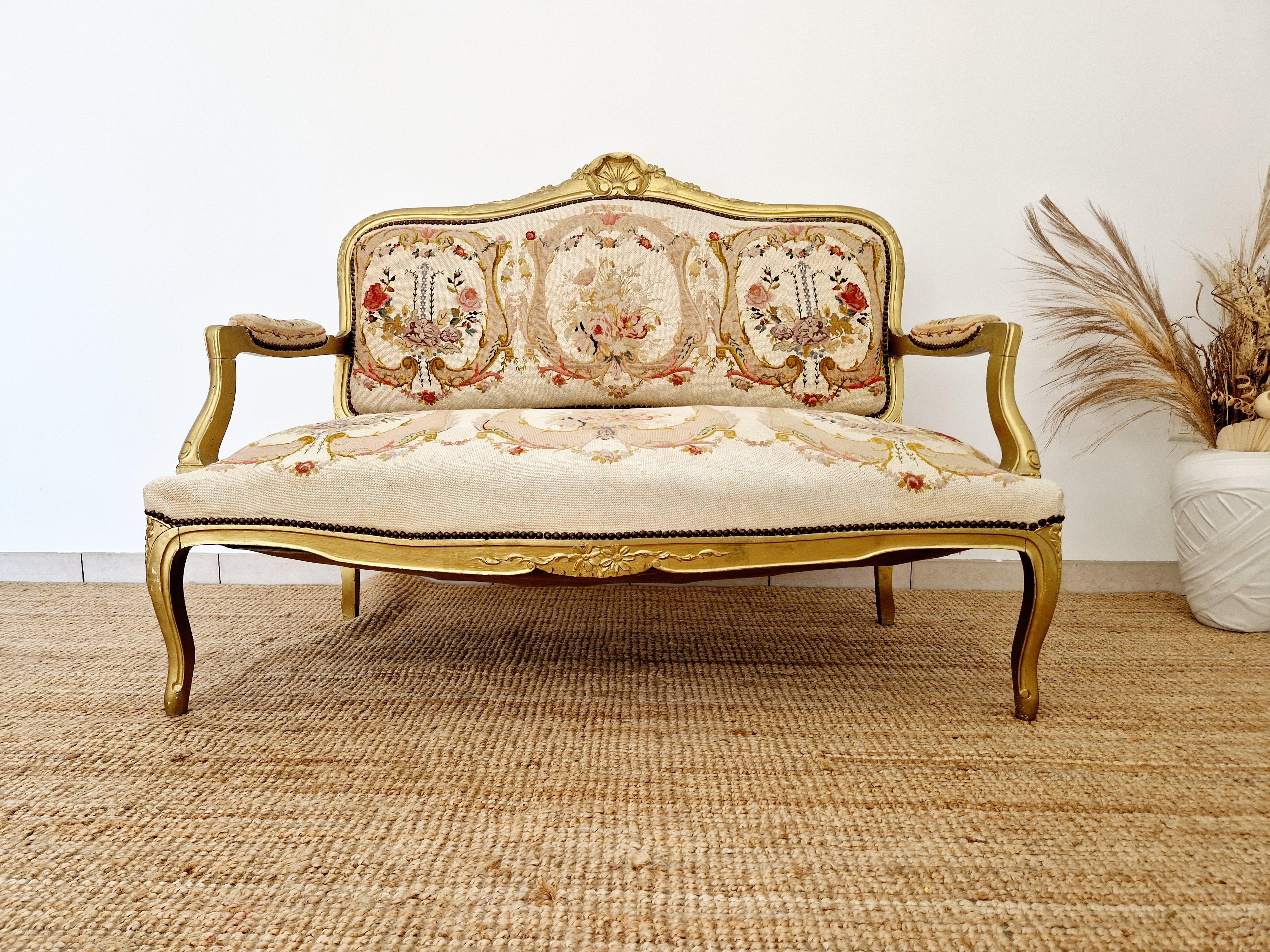 Ce canapé ancien de style Louis XV provient d'un château de l'ouest de la France. Datant de 1890, ce canapé respire l'élégance et la sophistication avec sa tapisserie à motifs floraux de couleur crème et son encadrement doré. Fabriqué en France dans