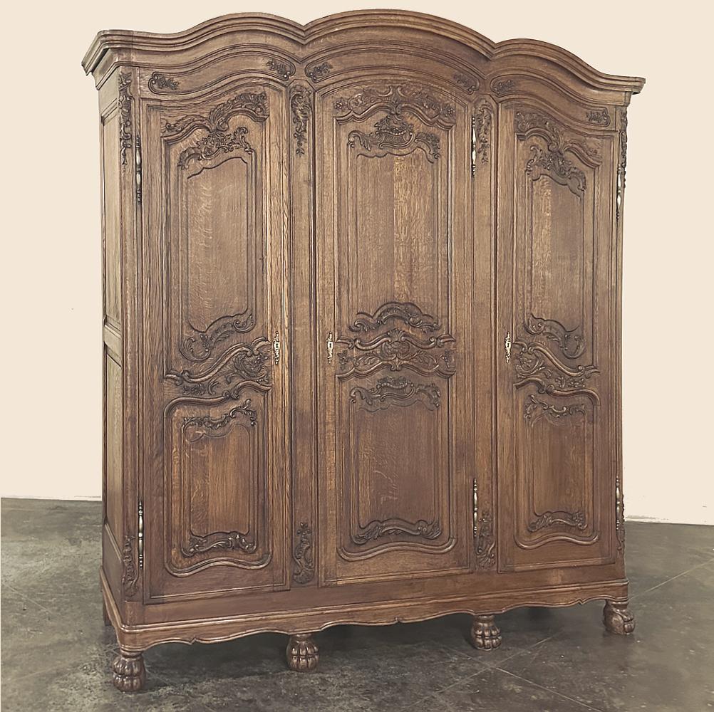 Antique French Louis XV Triple Armoire is a majestic example of one of the most recognizable French styles extant, influenced by both the Baroque and the Rococo to produce the artfully scrolled lines and lavish naturalistic carving that define the