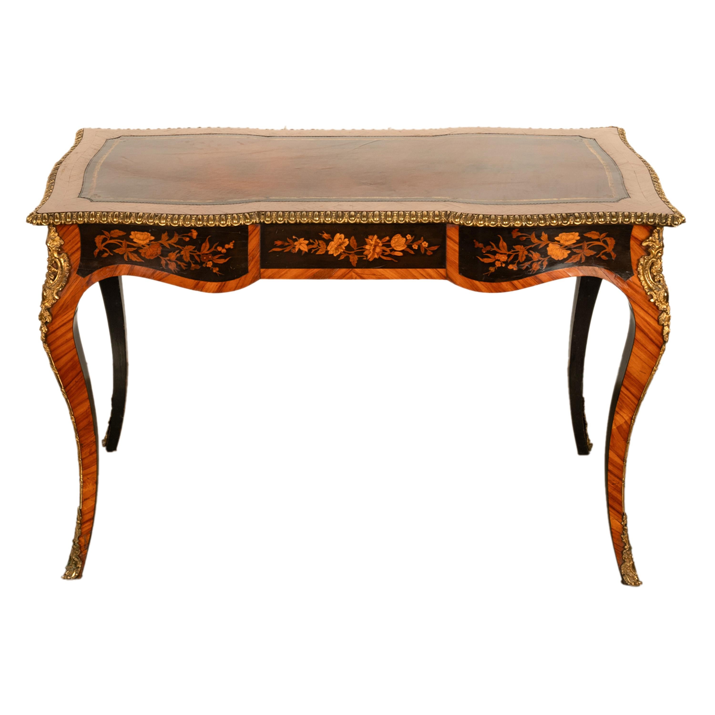 Precioso escritorio francés Luis XV antiguo del siglo XIX de madera de tulipán y marquetería, montado en ormolu, con forma de serpentina, hacia 1880.
La mesa tiene una superficie para escribir de cuero dorado y estampado en tonos marrones y rojos, y