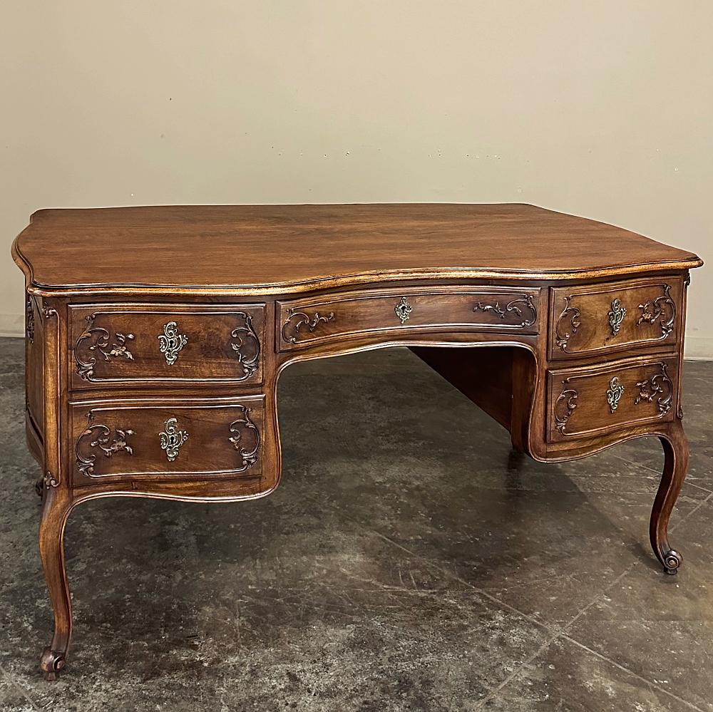 Der antike französische Louis-XV-Schreibtisch aus Nussbaum ist ein prächtiges Beispiel für diesen Stil. Er ist aus prächtigem Nussbaumholz und aufwändig gegossenem Messing gefertigt und bietet einen Arbeitsplatz wie kein anderer!  Die geschwungene,