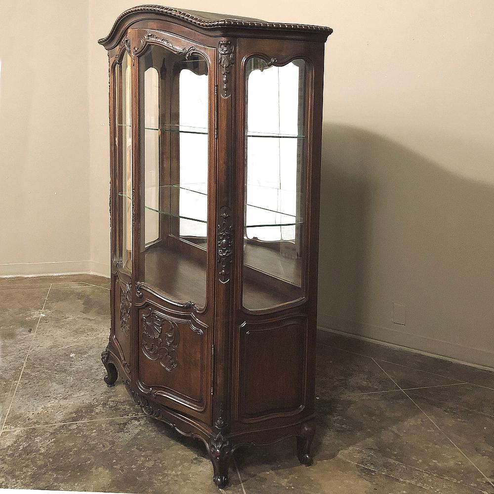 Antique French Louis XV walnut vitrine, Argentier is a splendid example of form married to function! Rendered by talented craftsmen from sumptuous French walnut, it features the Classic chapeau de gendarme crown overlooking a tastefully carved