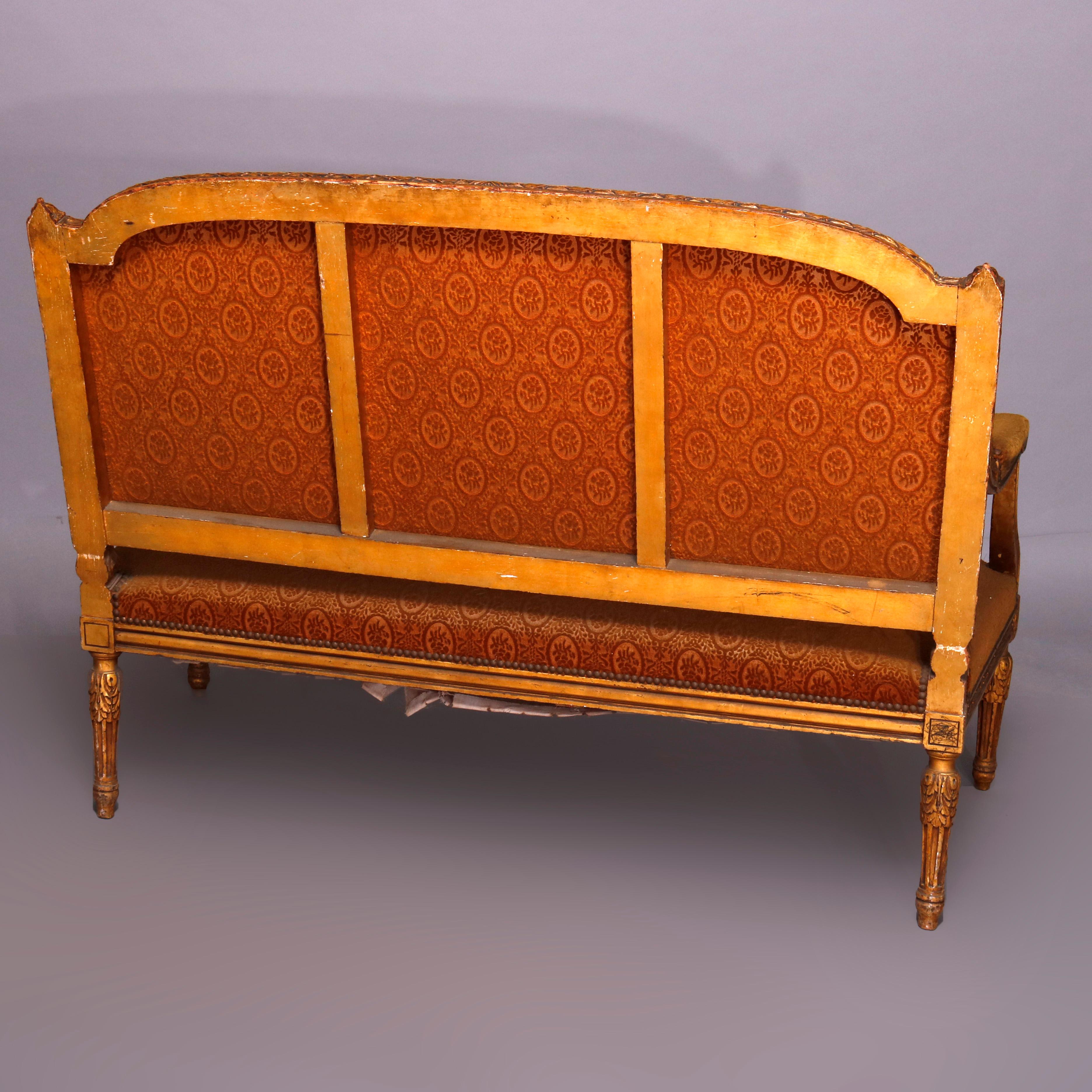 An antique French Louis XVI style settee offers carved giltwood frame with foliate bordering and rosettes, having upholstered back, seat and arms, raised on carved acanthus fluted legs, circa 1890

***DELIVERY NOTICE – Due to COVID-19 we have