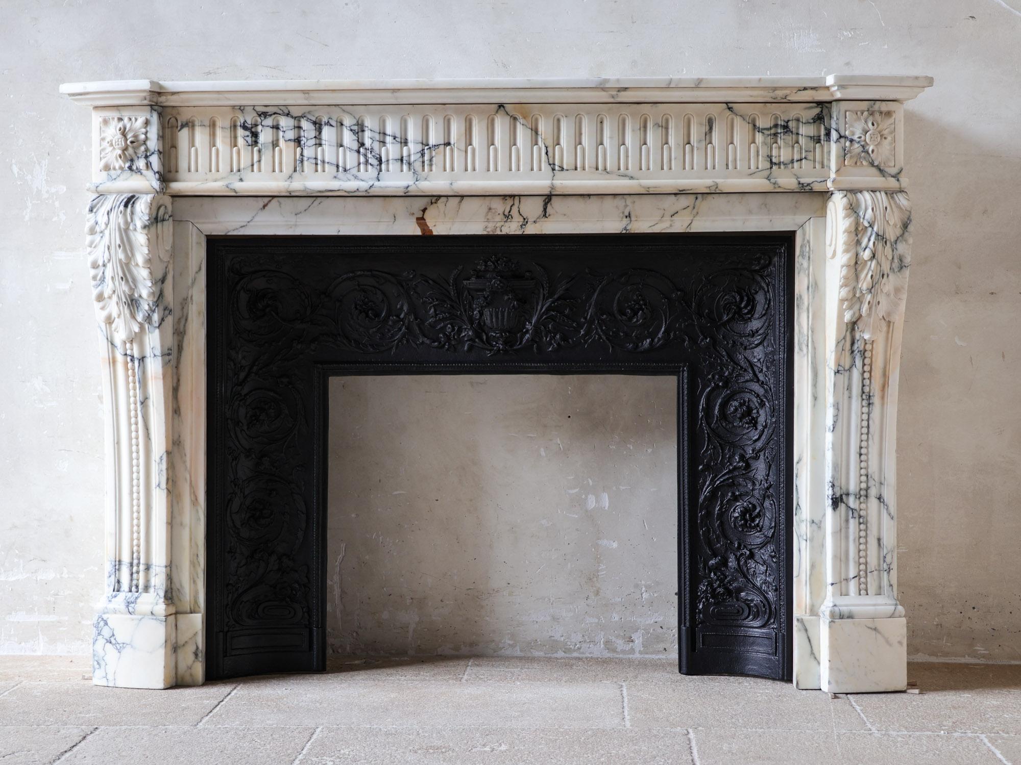 Dieser außergewöhnliche antike Louis XVI-Kamin ist aus Arabescato-Marmor gefertigt. Der Edelstein hat eine raffinierte, perlmuttartige Basis, die mit subtilen Mustern in Violett und einem Hauch von Pfirsichgold durchzogen ist - das Ergebnis ist ein