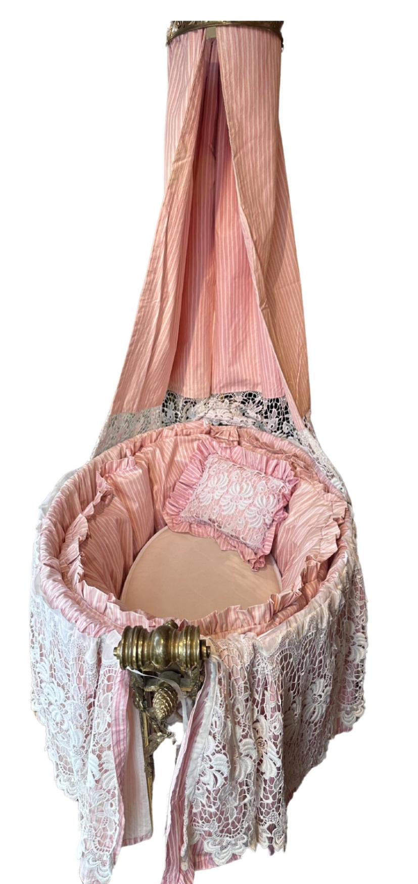 Antique French Louis XVI Brass Cradle With Crown & Silk. It includes the original crown and pink silk and Norfolk lace drape and bedding.  Provenance: we will include the original newspaper article from the 70s when it was discovered in a London