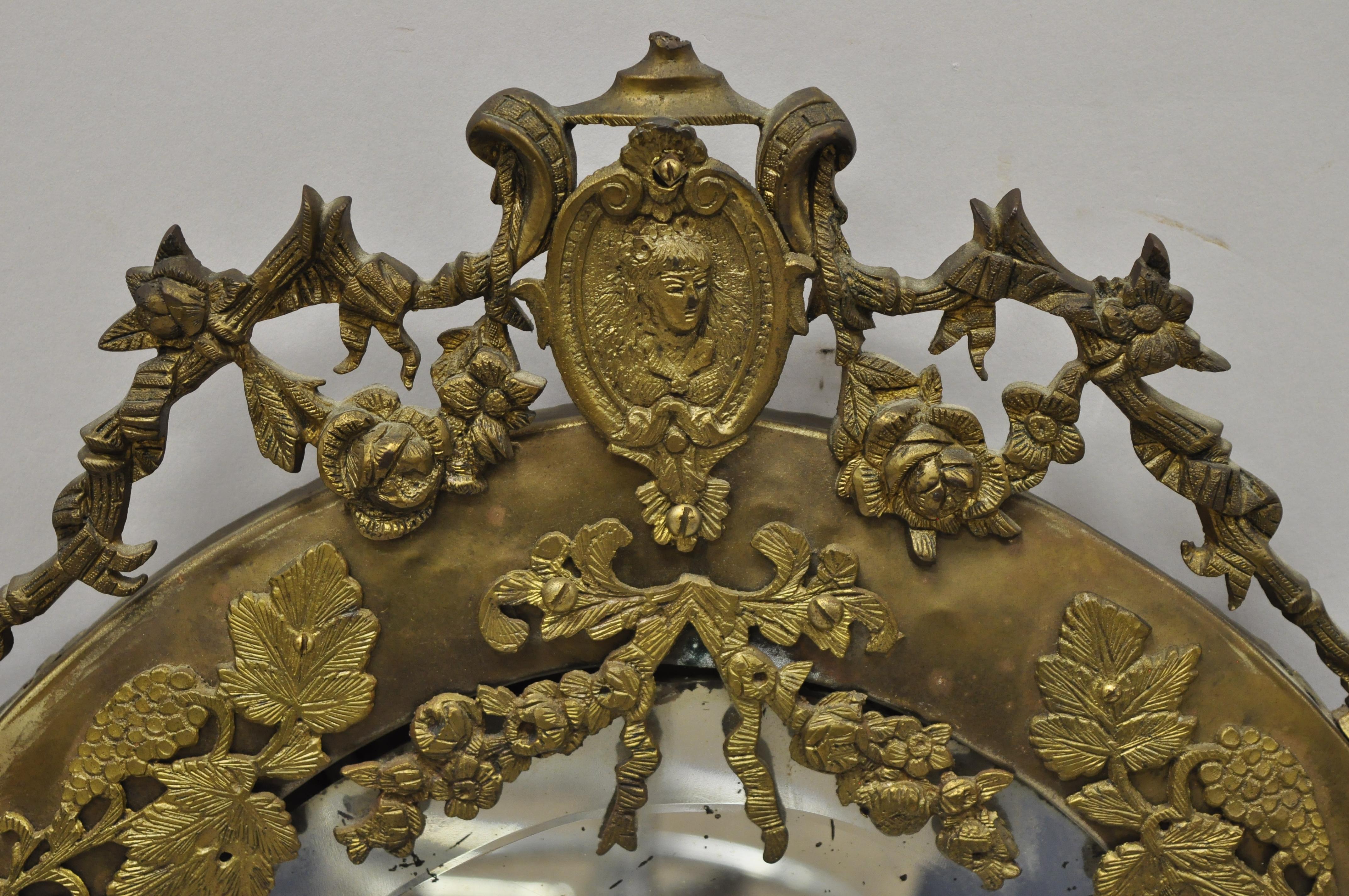 Ancien miroir français Louis XVI avec cadre en laiton, verre ovale biseauté et bronze doré. L'article présente un cadre en laiton patiné, un bronze ornemental, un verre ovale biseauté, un très bel article ancien, vers la fin du 19e siècle. Mesures :