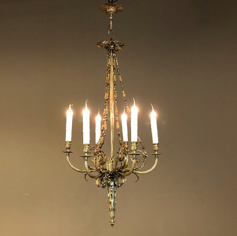 Antique French Louis XVI style bronze chandelier is a spectacular design, inspired by ancient Greek and Roman architecture! The original canopy survives, cast to depict a laurel rosette, which leads the eye down to the top of the fixture which has