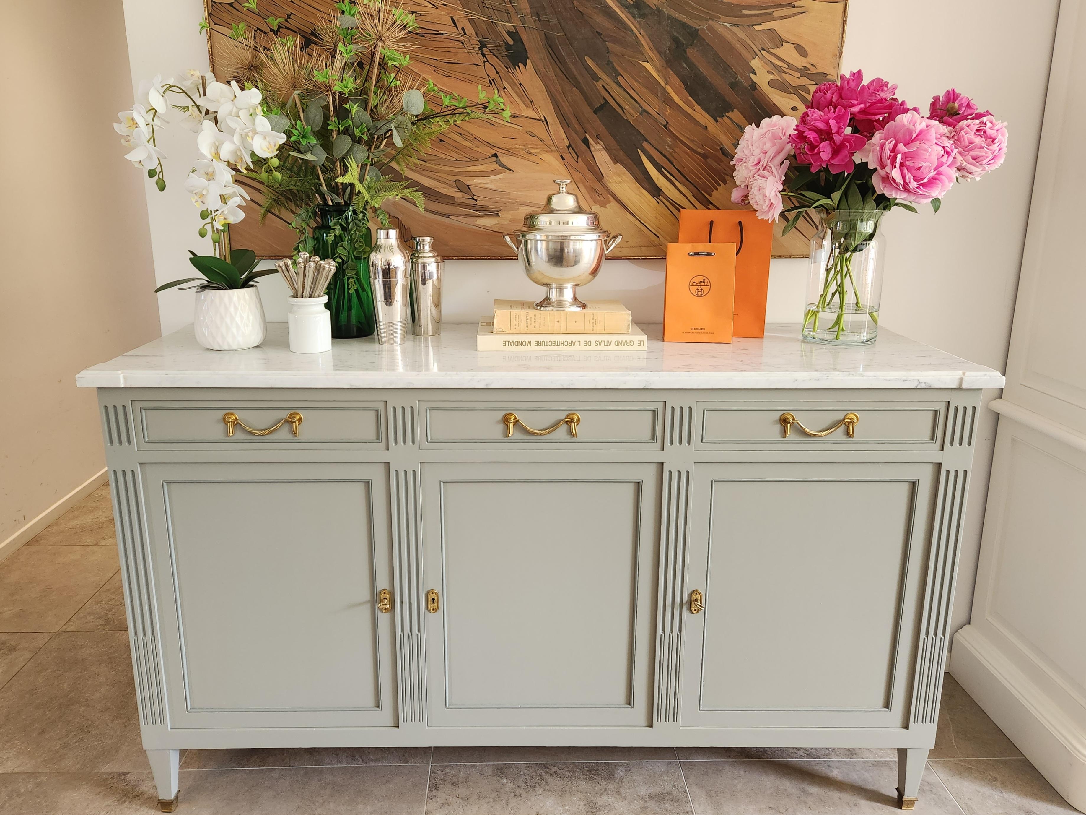 Antique French Louis XVI buffet topped with a Carrara marble, fluted legs finished with golden bronze clogs.
Three dovetailed drawers and doors, two keys.
Interior shelves removable in height. A very beautiful piece for a living room or dining room,