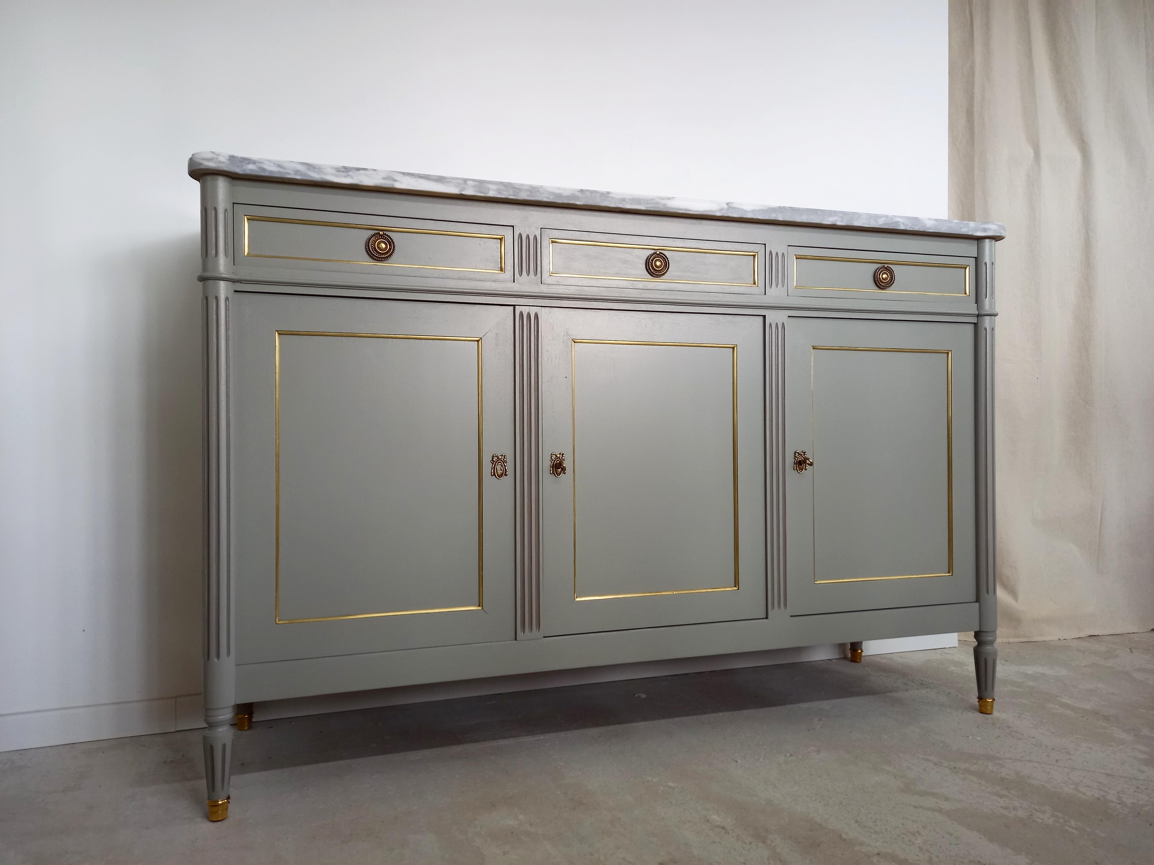 Antique French, Louis XVI style buffet topped with a superb white and grey marble, fluted legs finished with golden bronze clogs.
Three dovetailed drawers and doors with brass and bronze details, 2 keys.