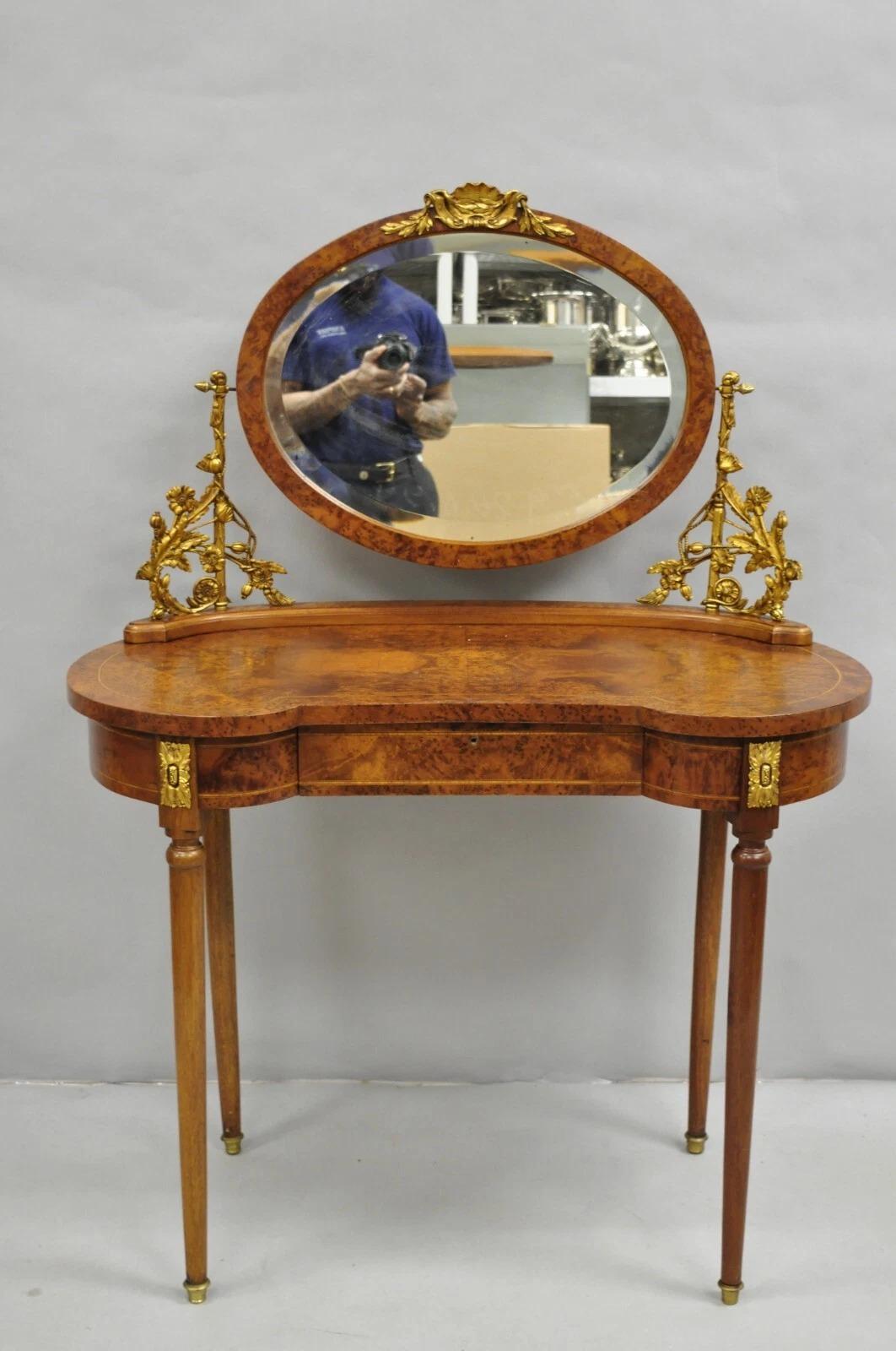 Antique French Louis XVI Style Burlwood Kidney Shaped Vanity Dressing Table with Mirror. Item features stunning gilt bronze ormolu, tapered legs, single dovetailed drawer with faux lock, pencil inlay, and oval beveled glass pivoting mirror. Circa